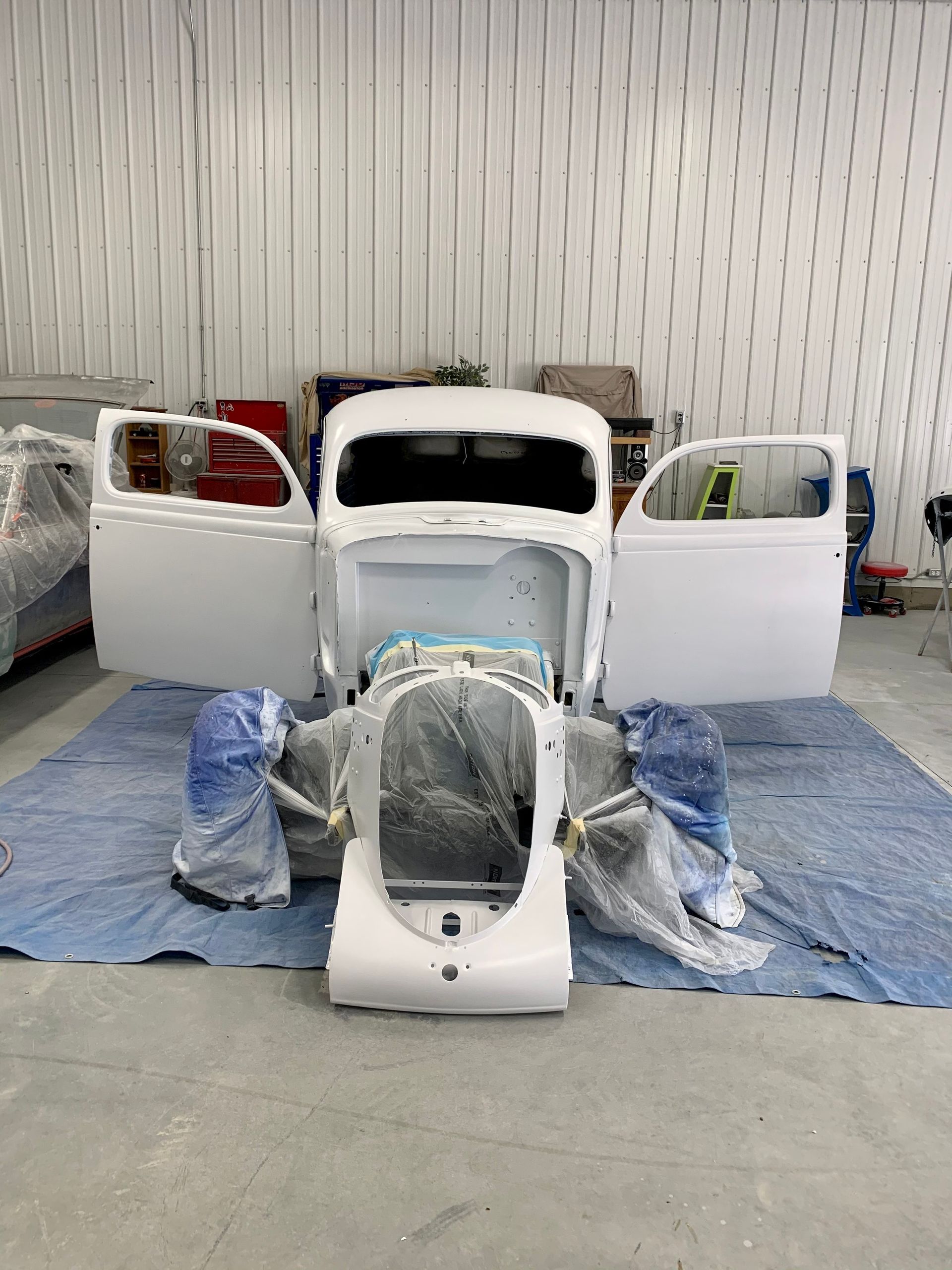 A white car is being painted in a garage.