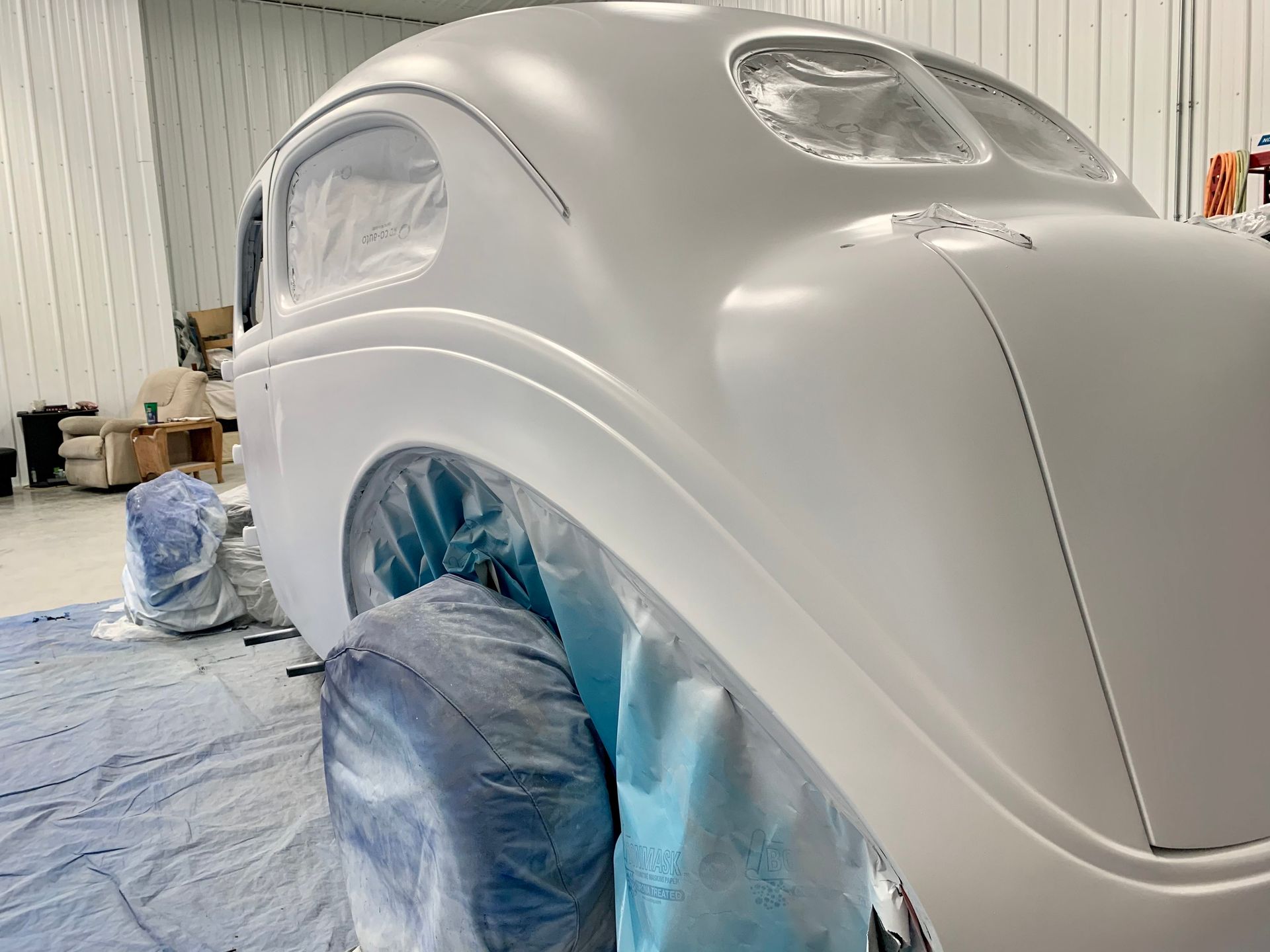 A white car is being painted in a garage.