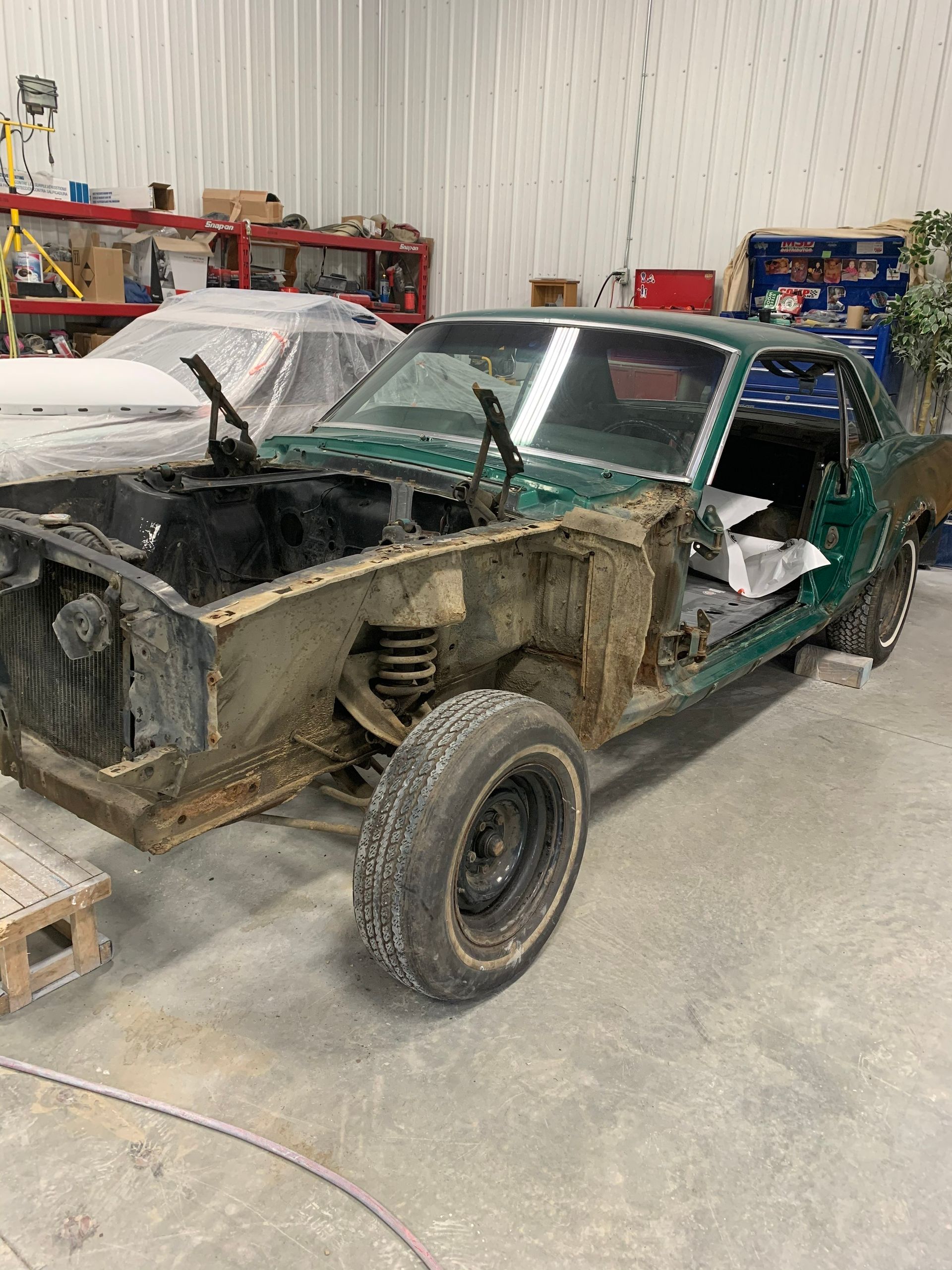A green car is being built in a garage.