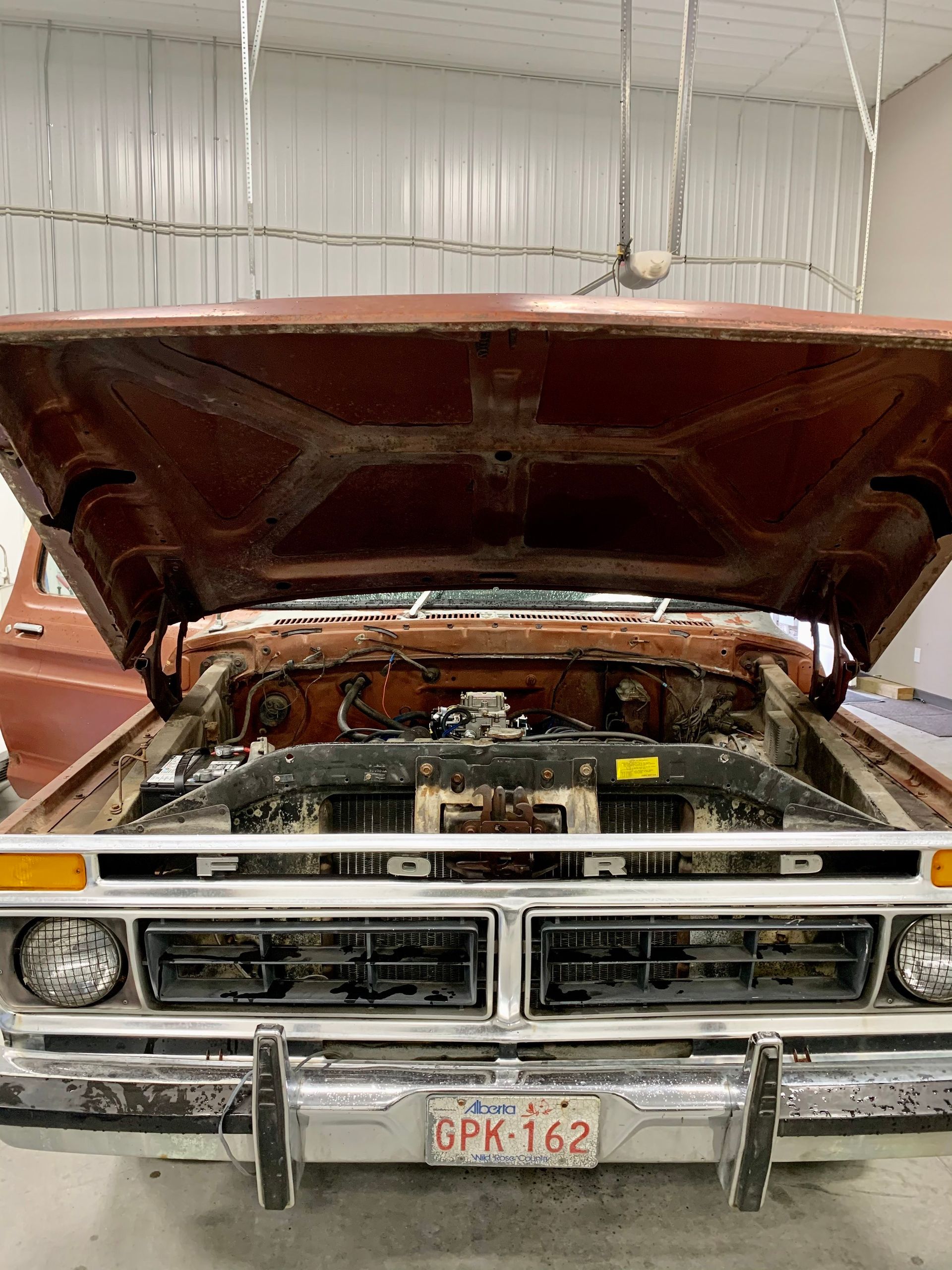 A truck with the hood up is sitting in a garage.