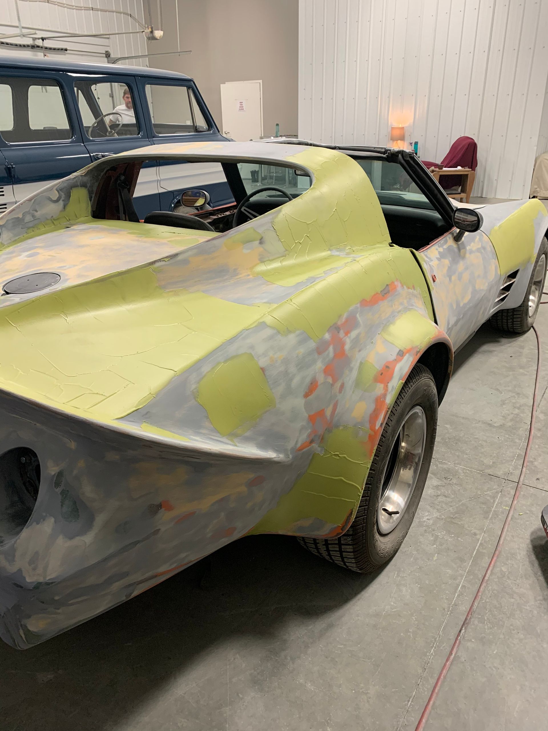 A yellow car is being painted in a garage