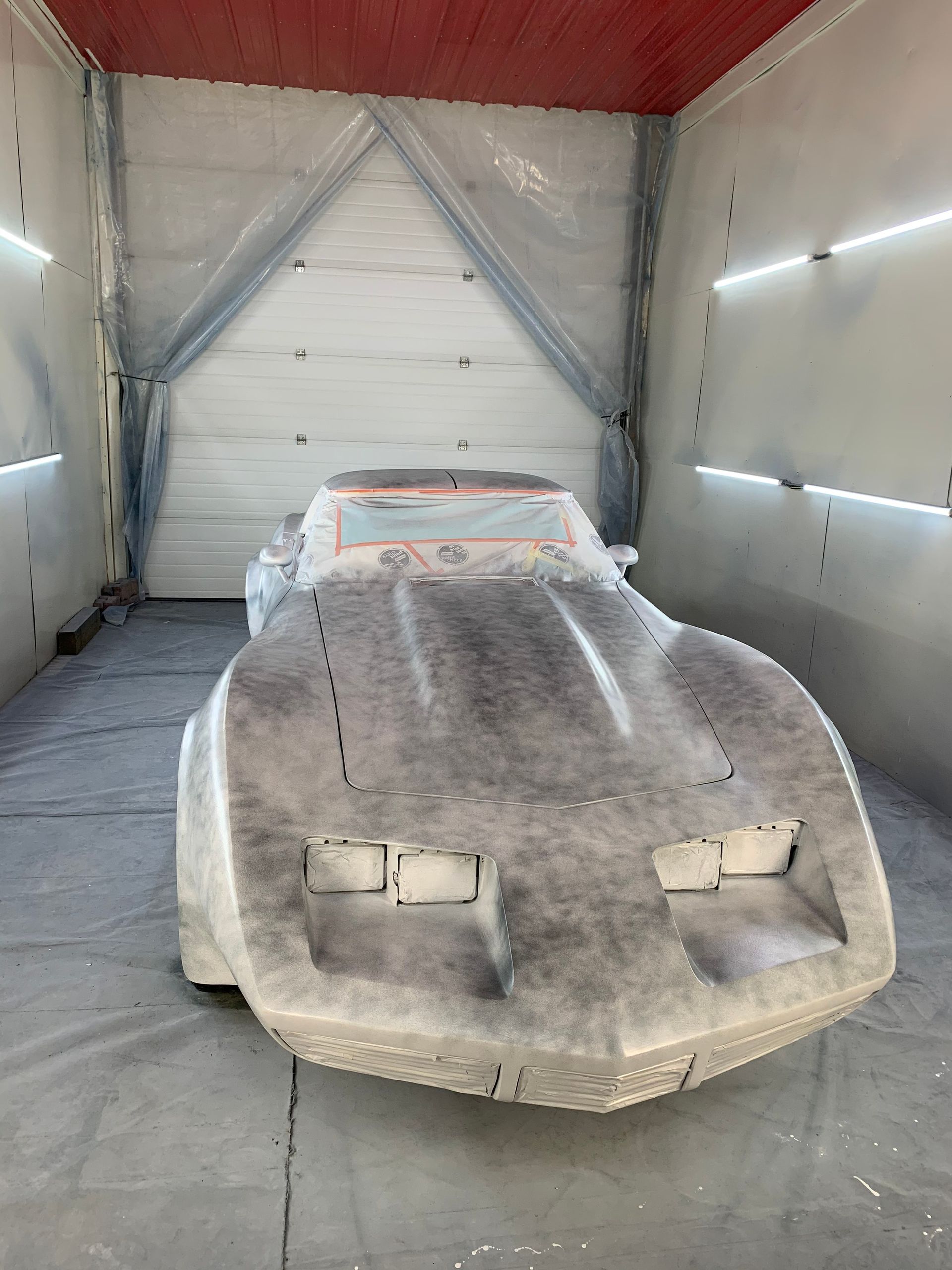 A car is being painted in a garage.