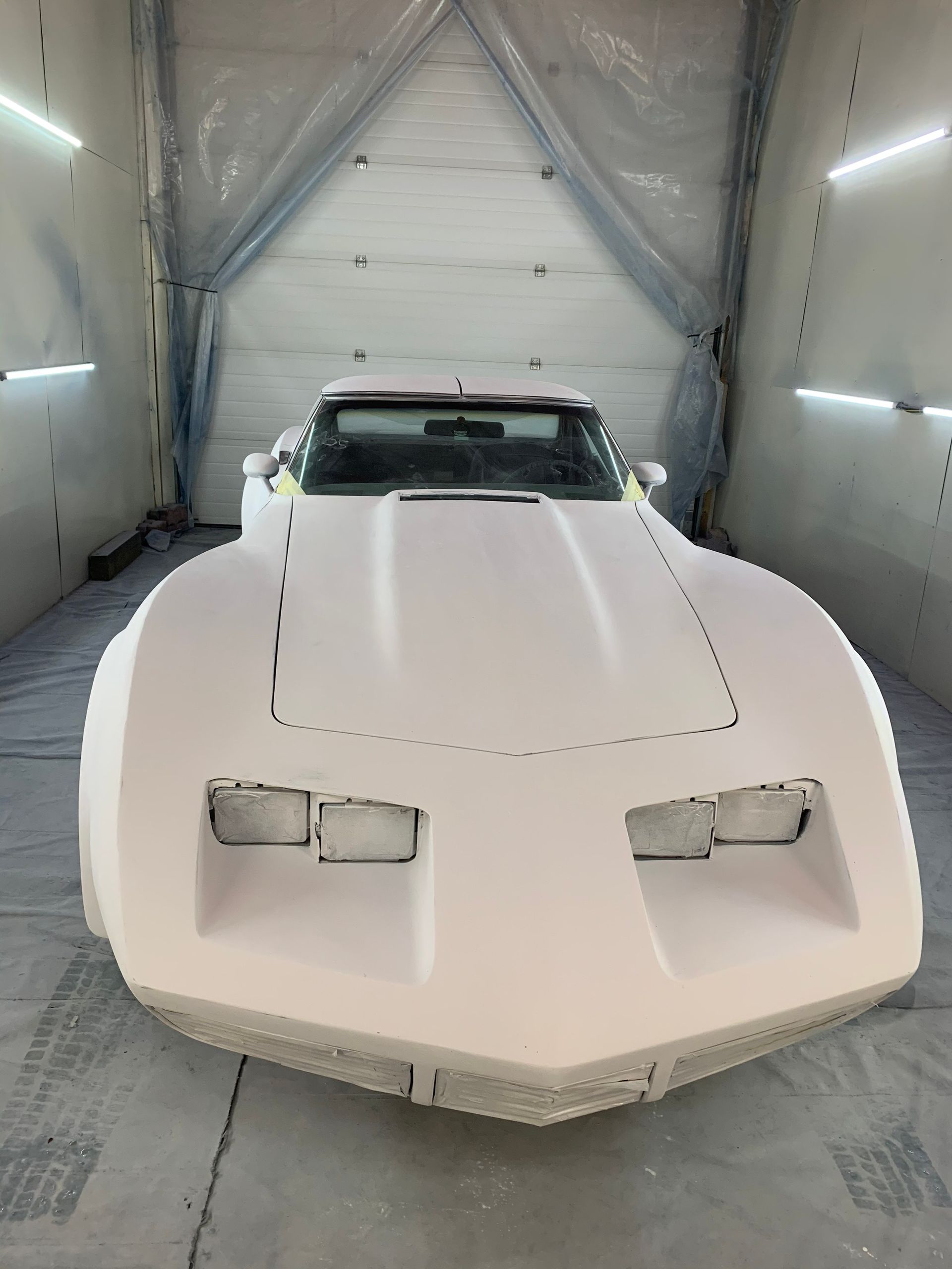 A white car is sitting in a garage under a tarp