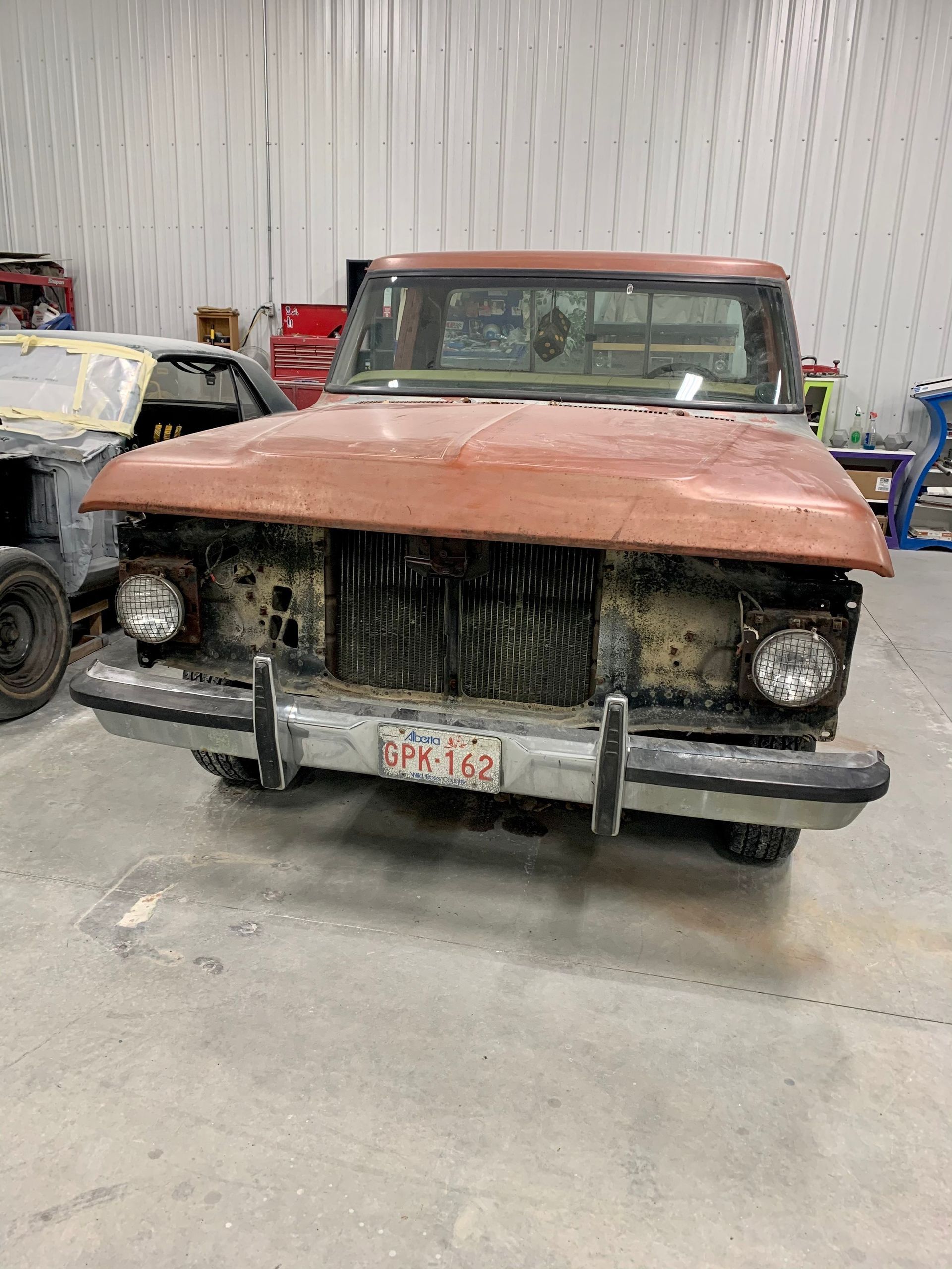 An old rusty truck is parked in a garage.