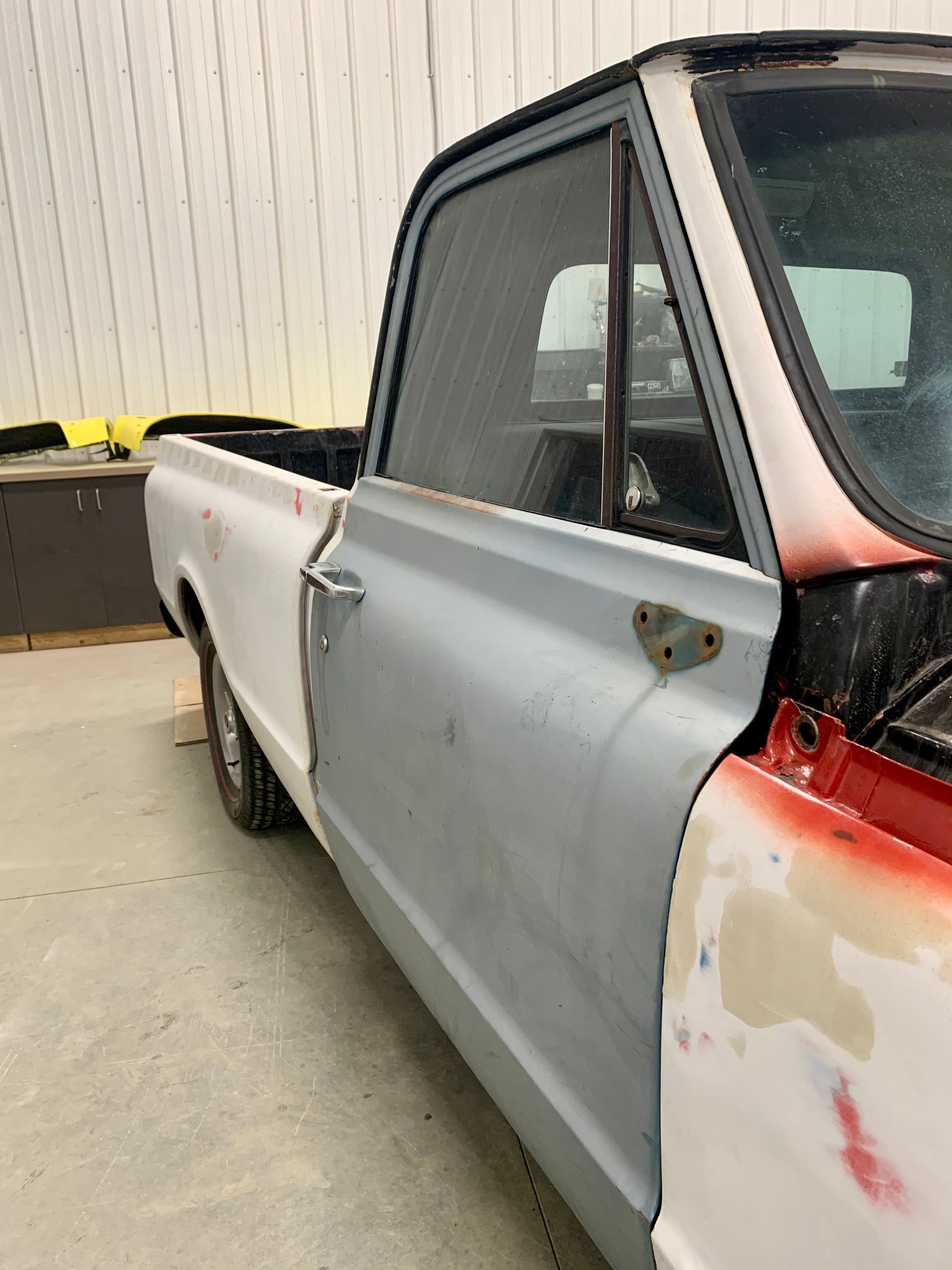 A white and red truck is parked in front of a building.