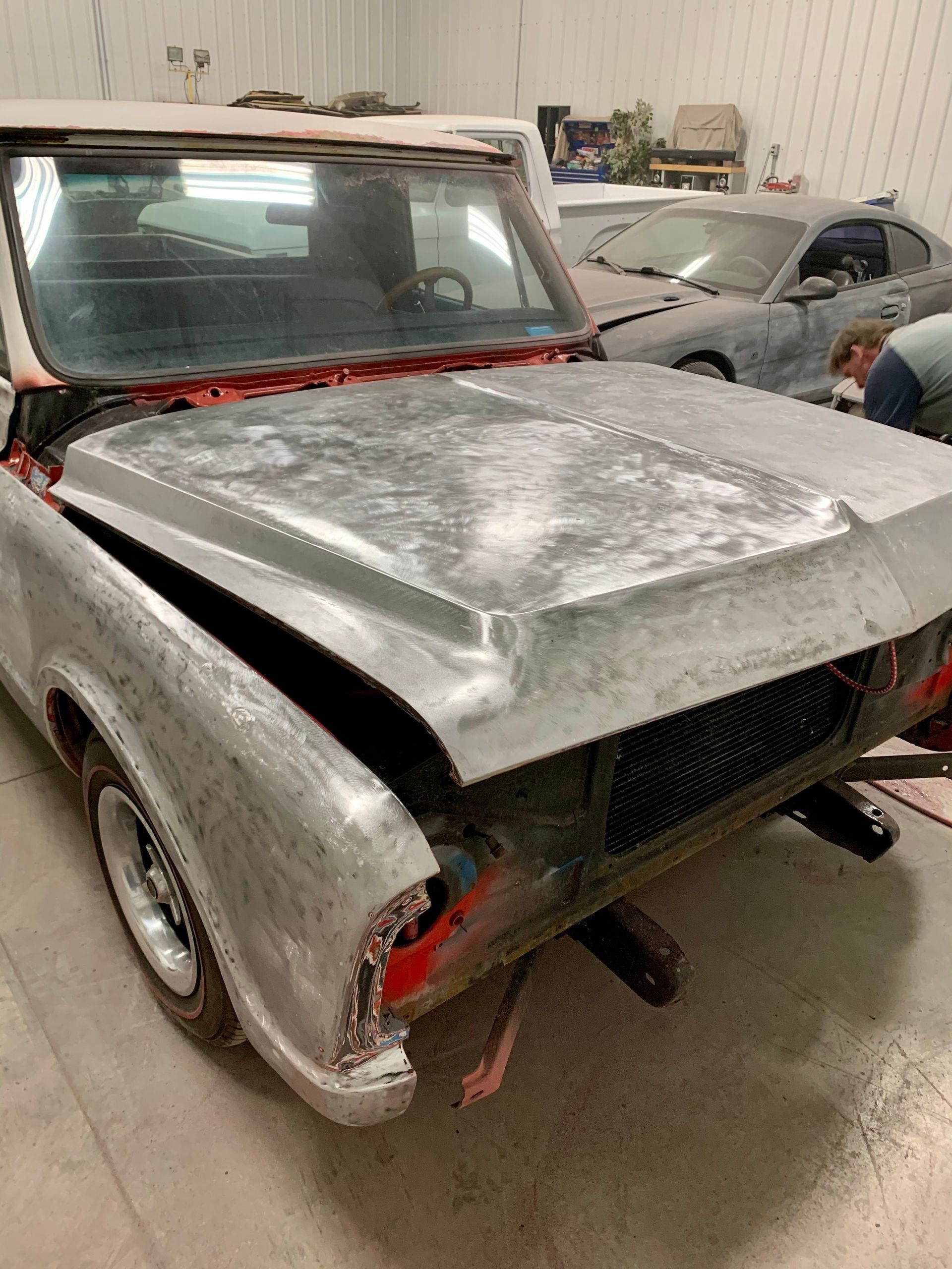 A car with a broken hood is sitting in a garage.