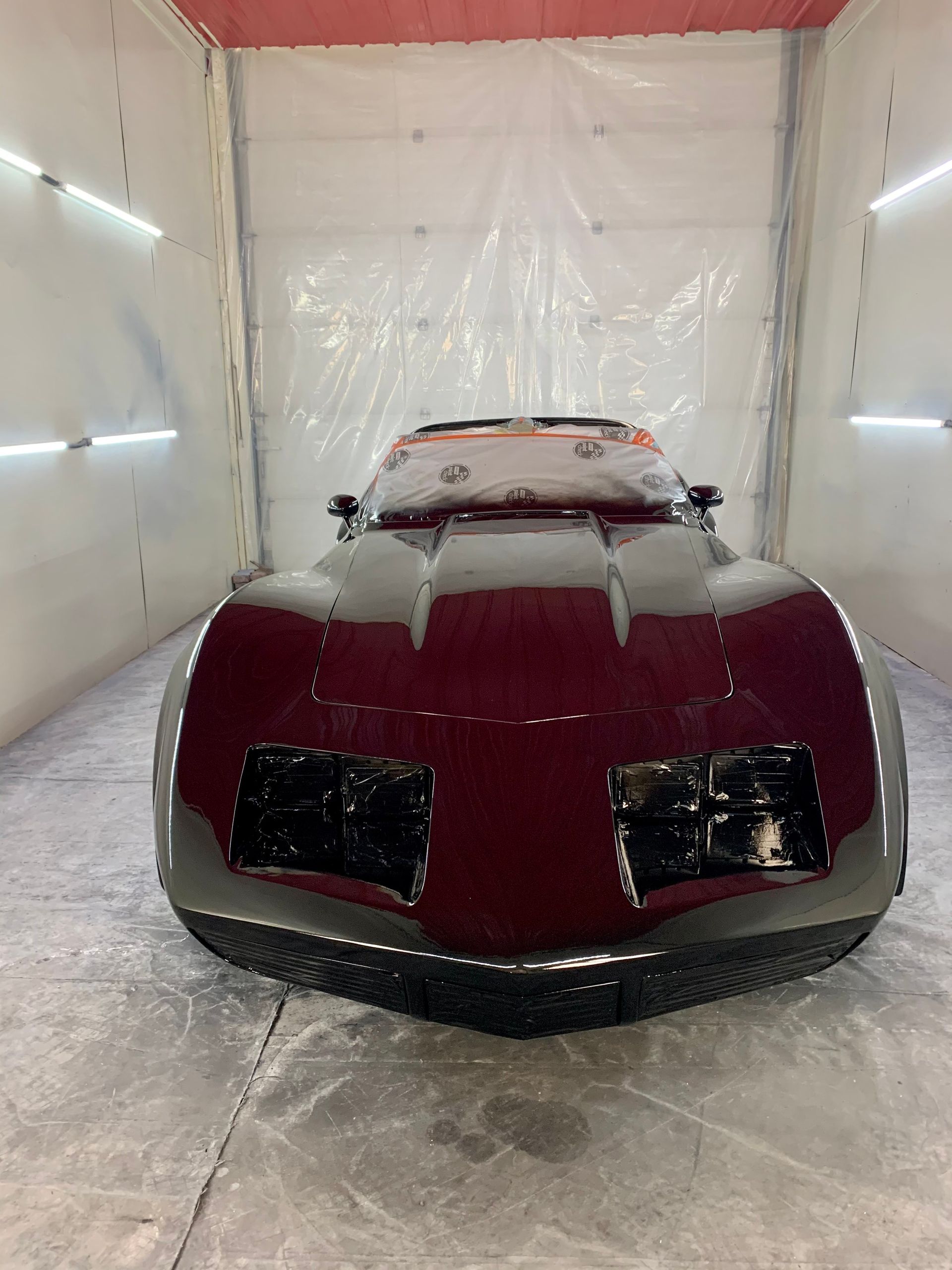 A red corvette is sitting in a paint booth.