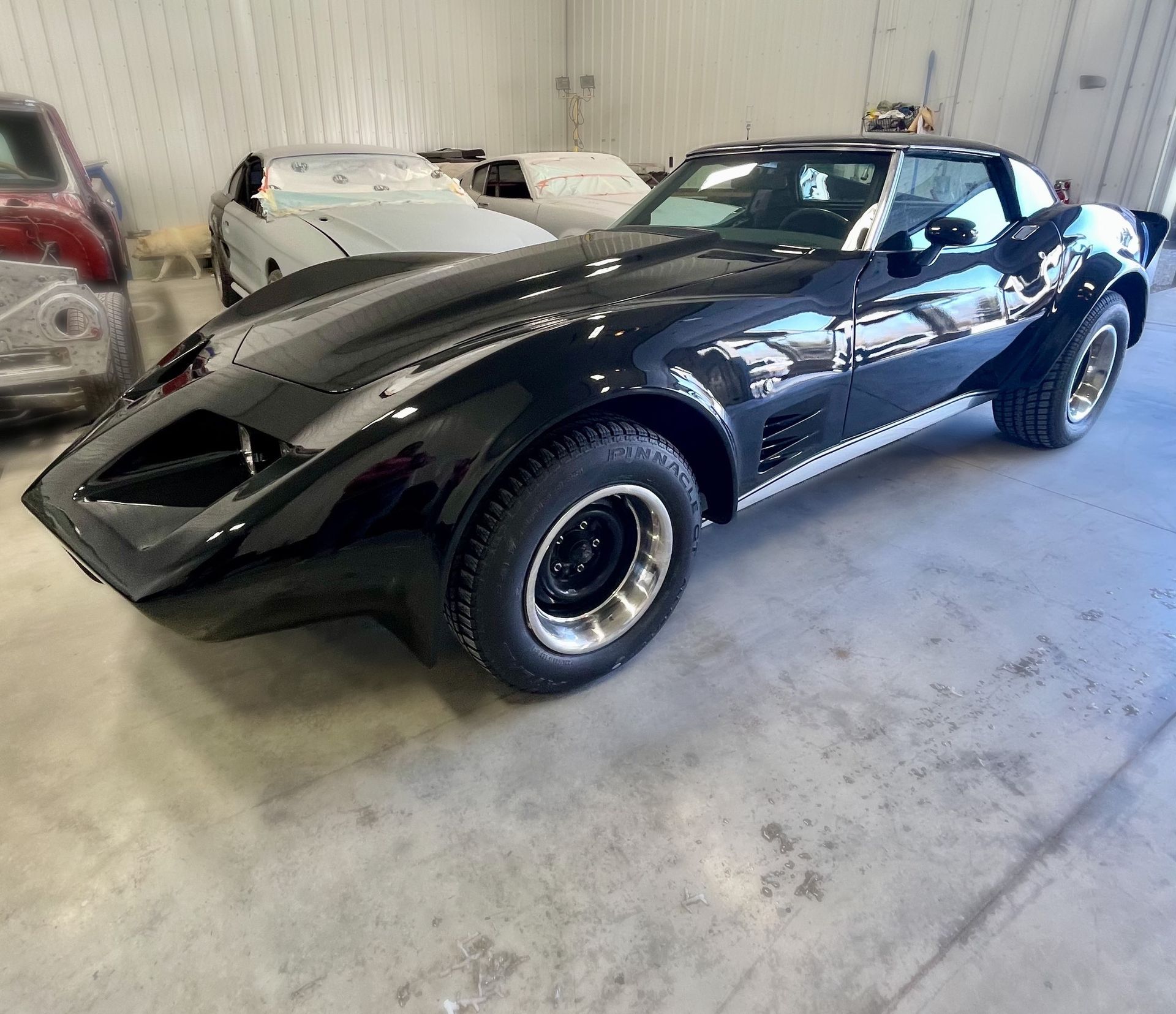 A black corvette is parked in a garage.