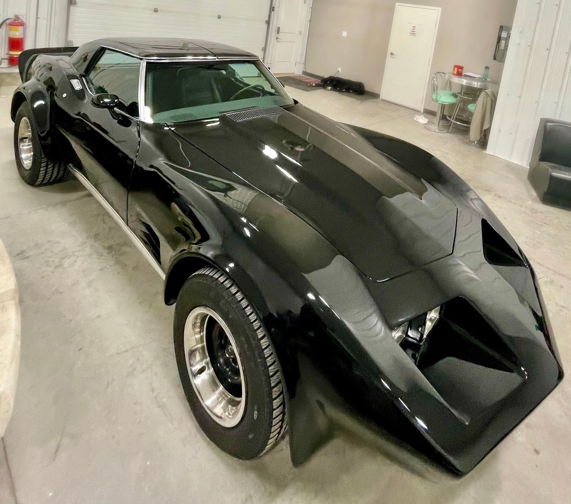 A black corvette is parked in a garage.