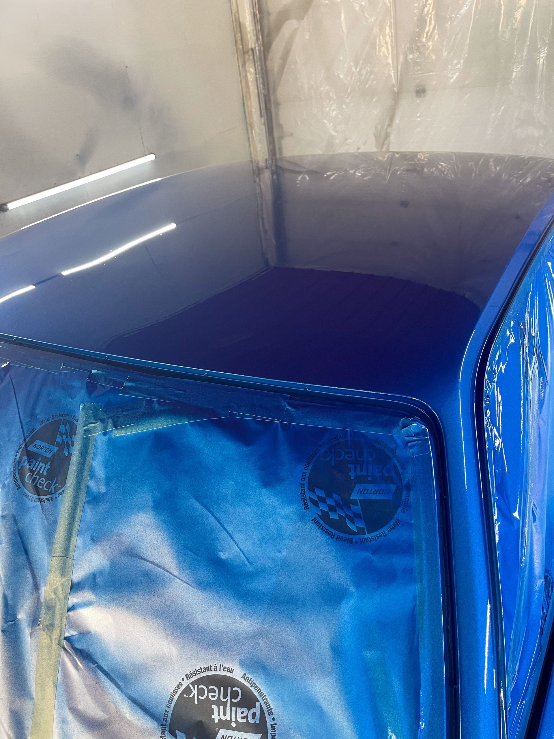 A blue tarp is covering the roof of a car