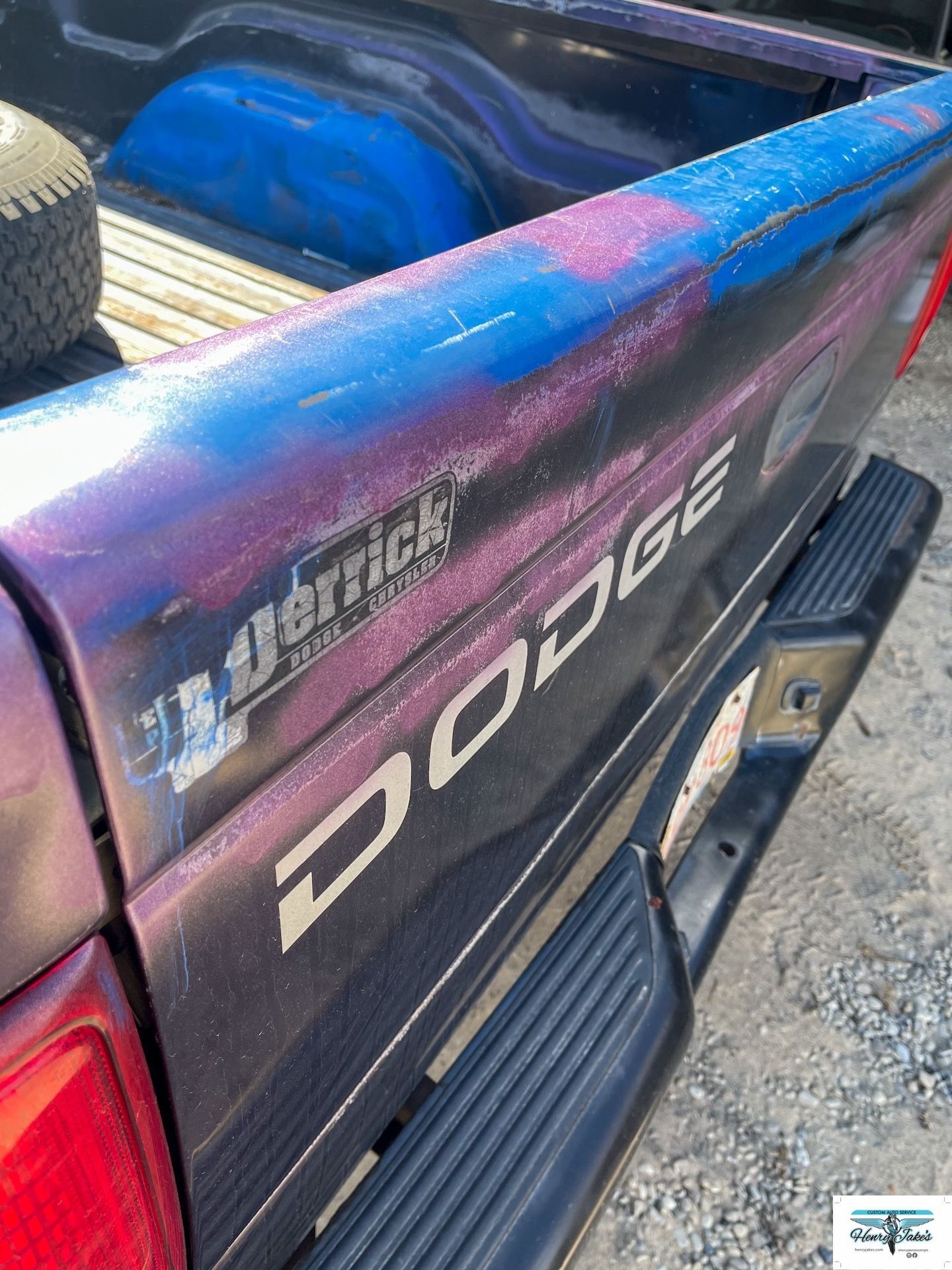 The back of a purple dodge truck with a sticker on it.