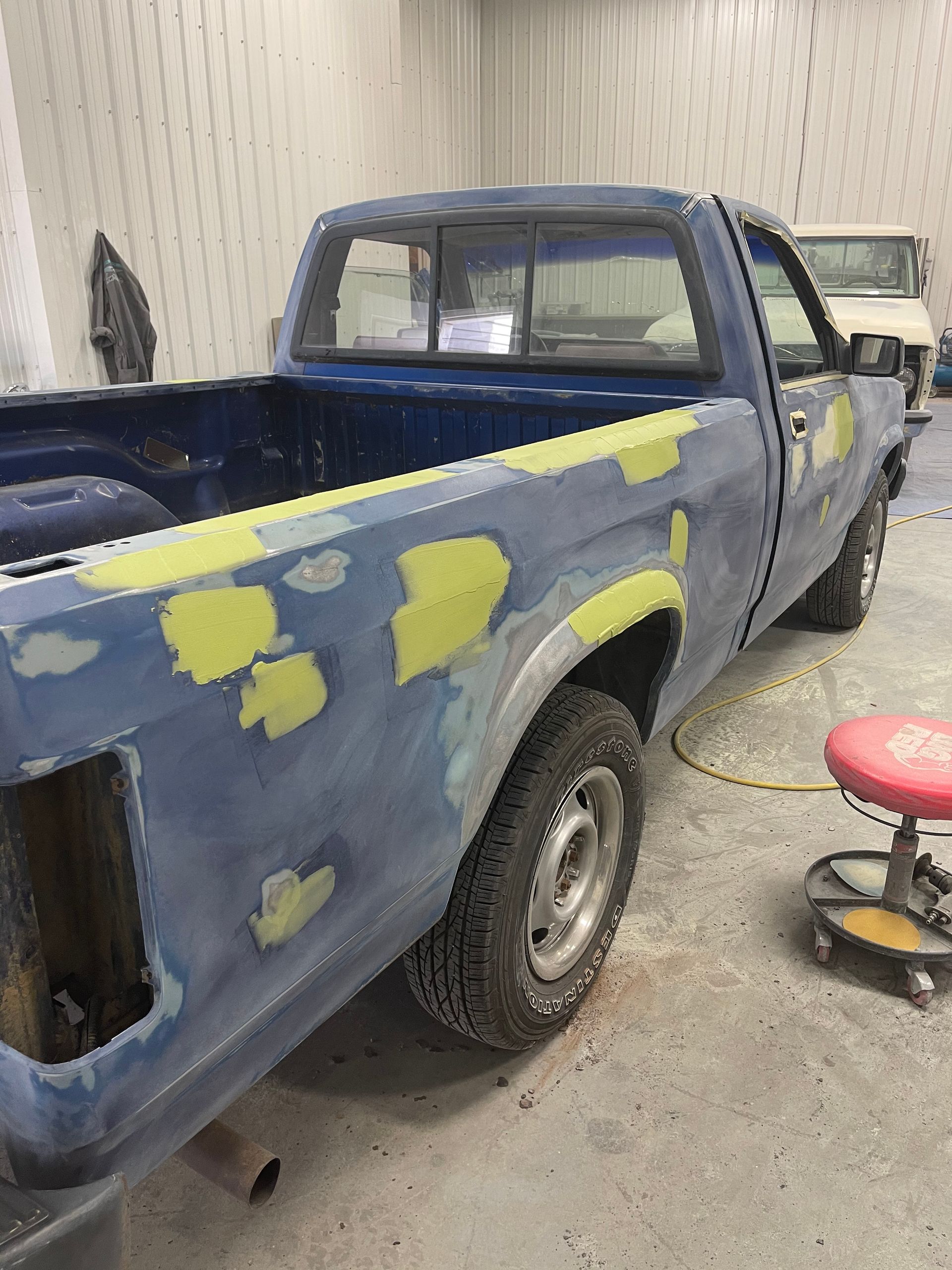 A blue truck is being painted in a garage.