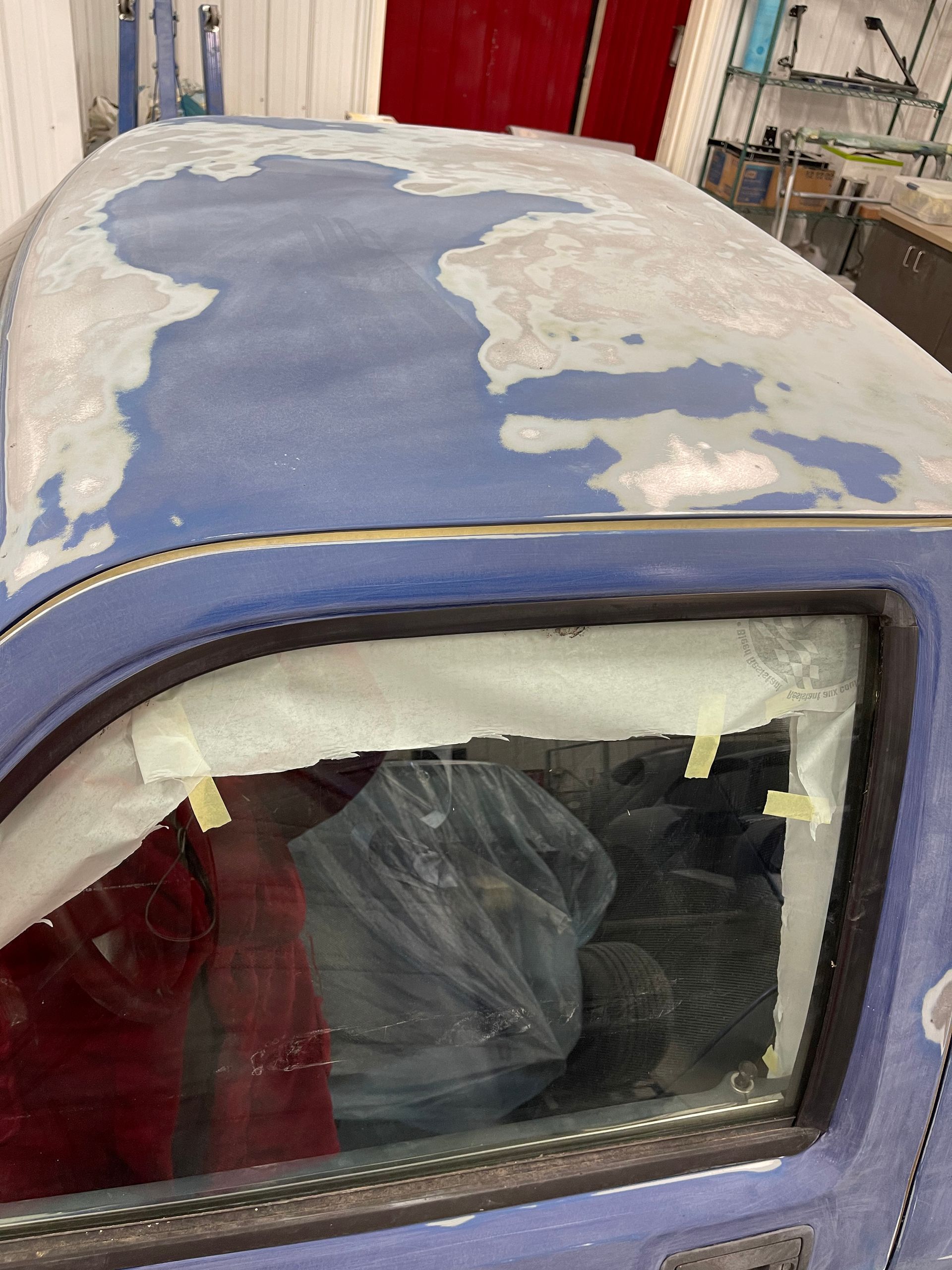 The roof of a blue truck is being painted.
