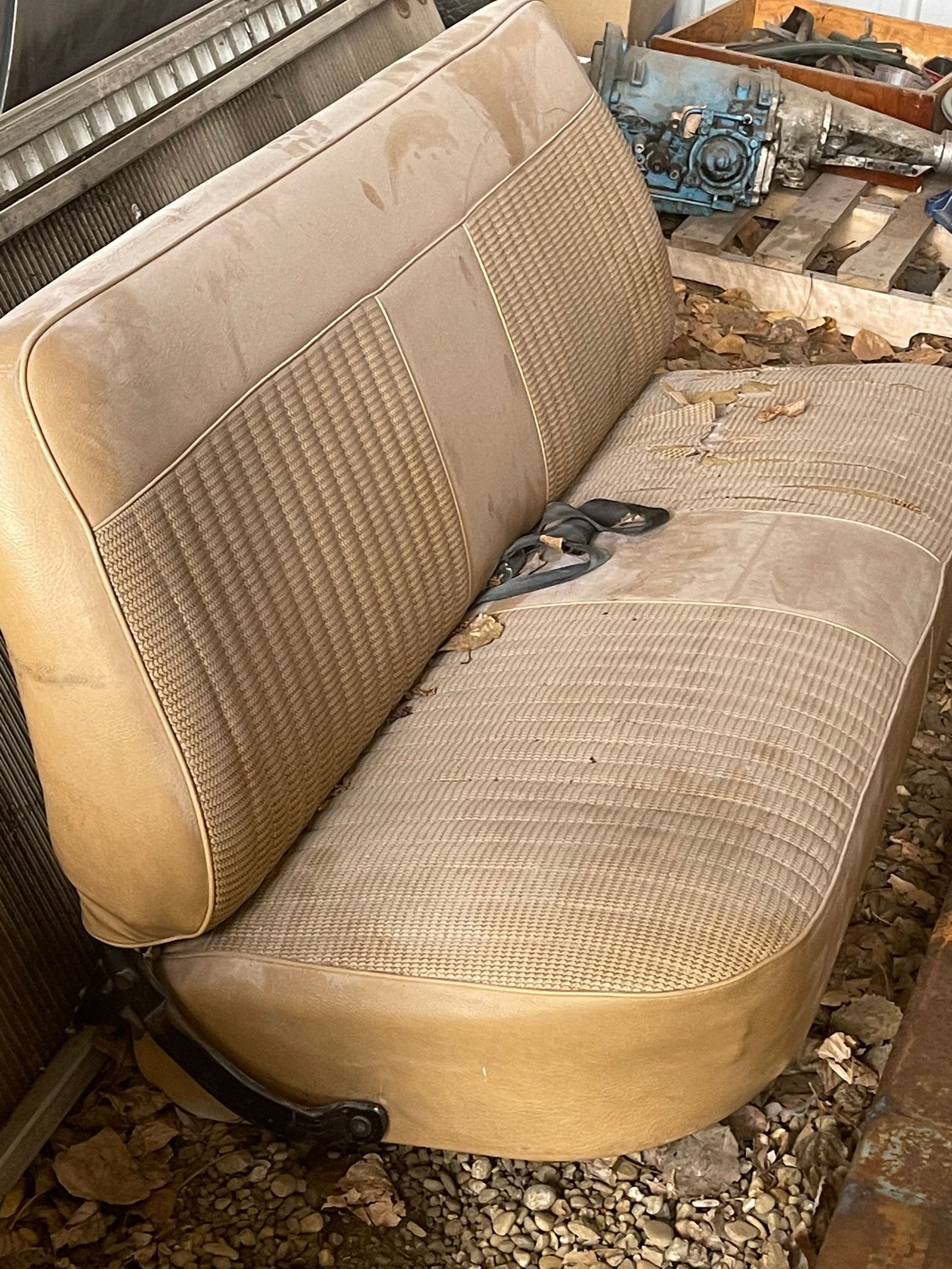 An old car seat is sitting on a pile of rocks.