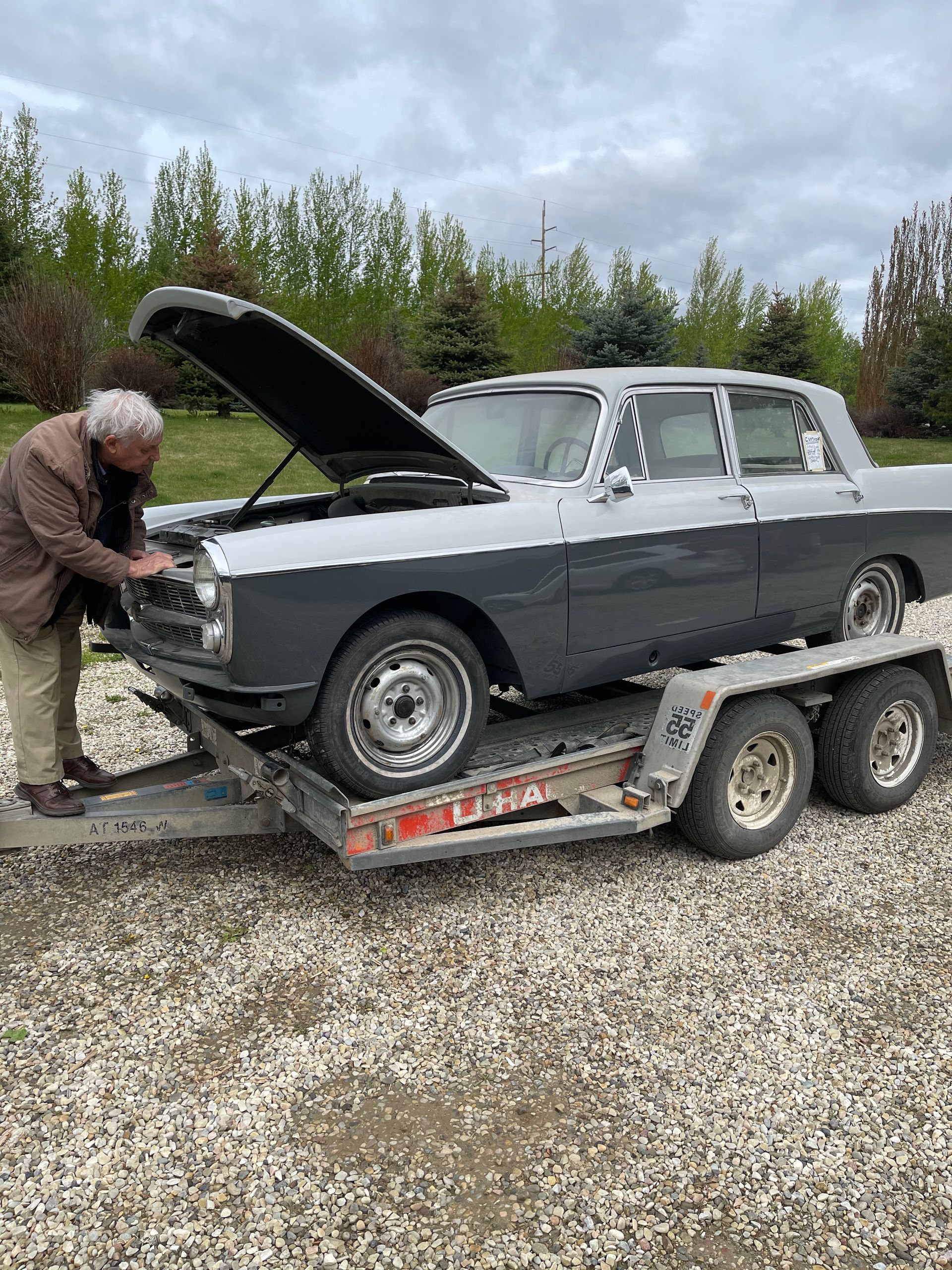 A man is working on a car on a trailer.
