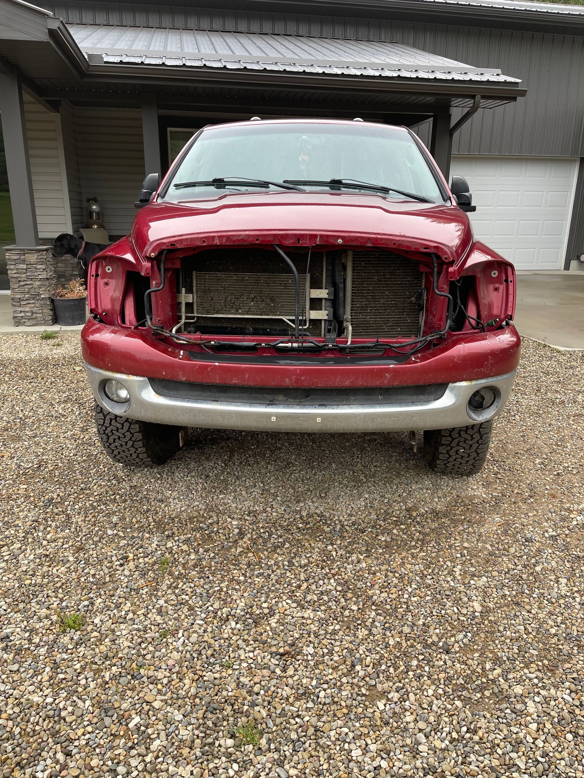 A red truck is parked in a gravel lot in front of a house.