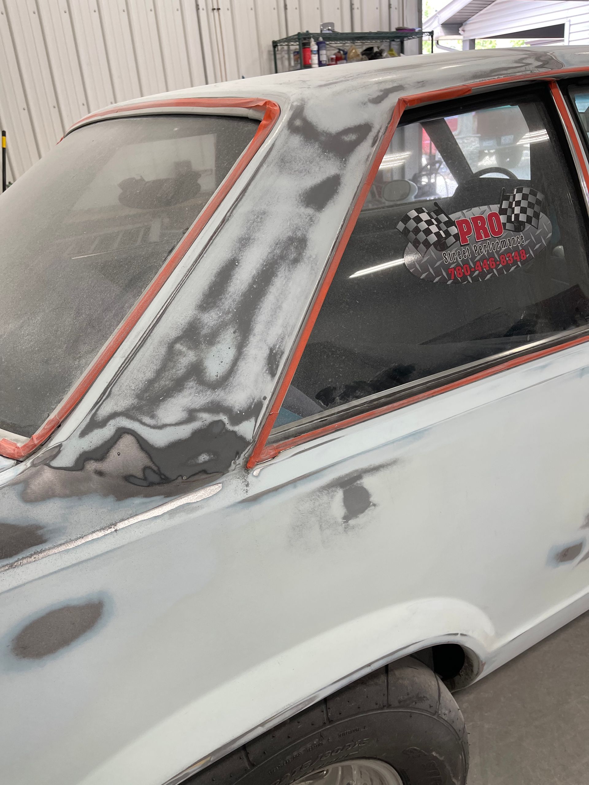 A white car is being painted in a garage.