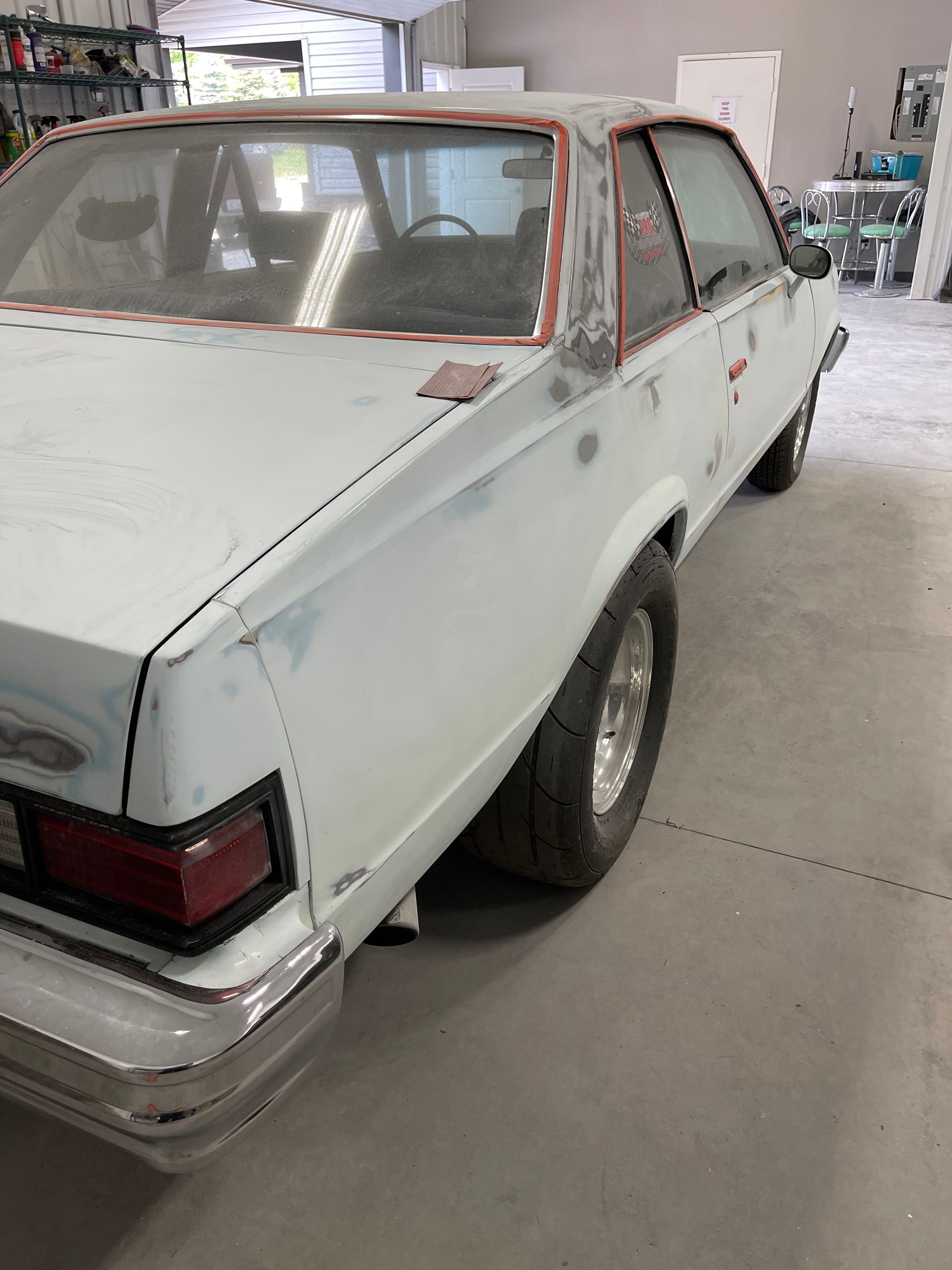 A white car is sitting in a garage waiting to be painted.