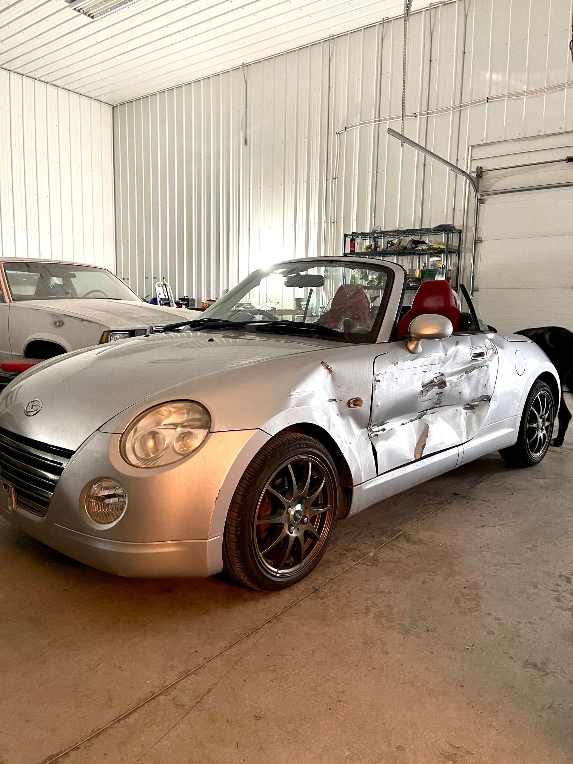 A silver convertible sports car is parked in a garage.