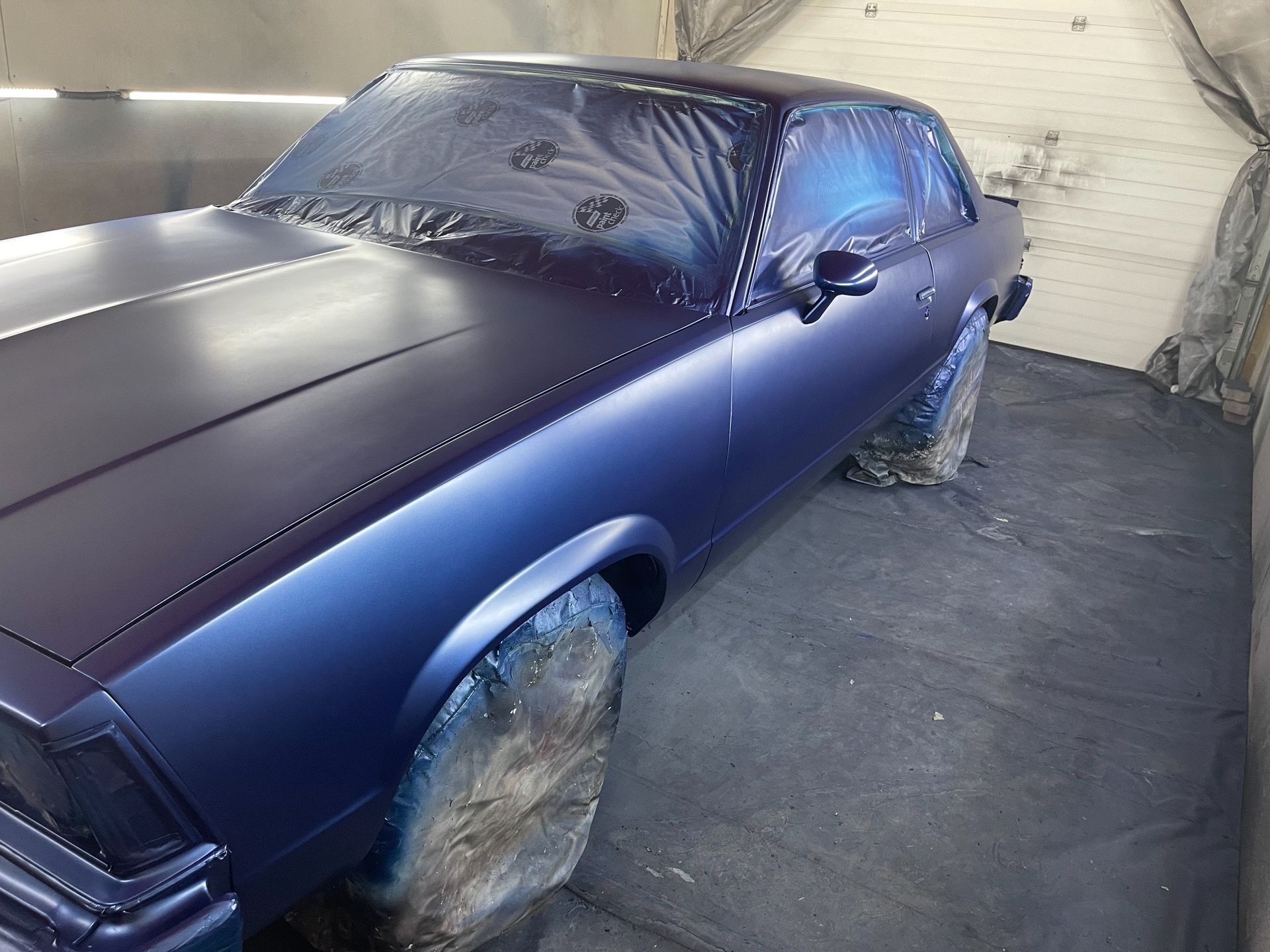 A purple car is painted in a garage.