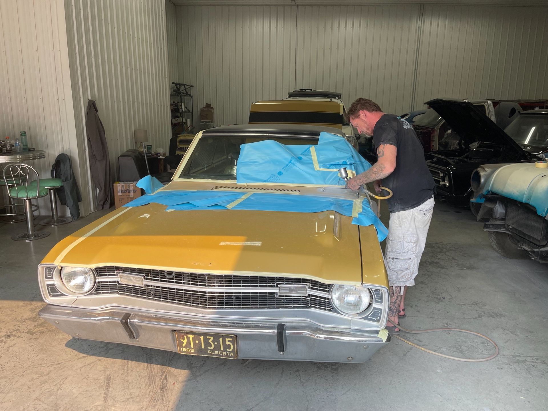 A man is working on a yellow car in a garage.