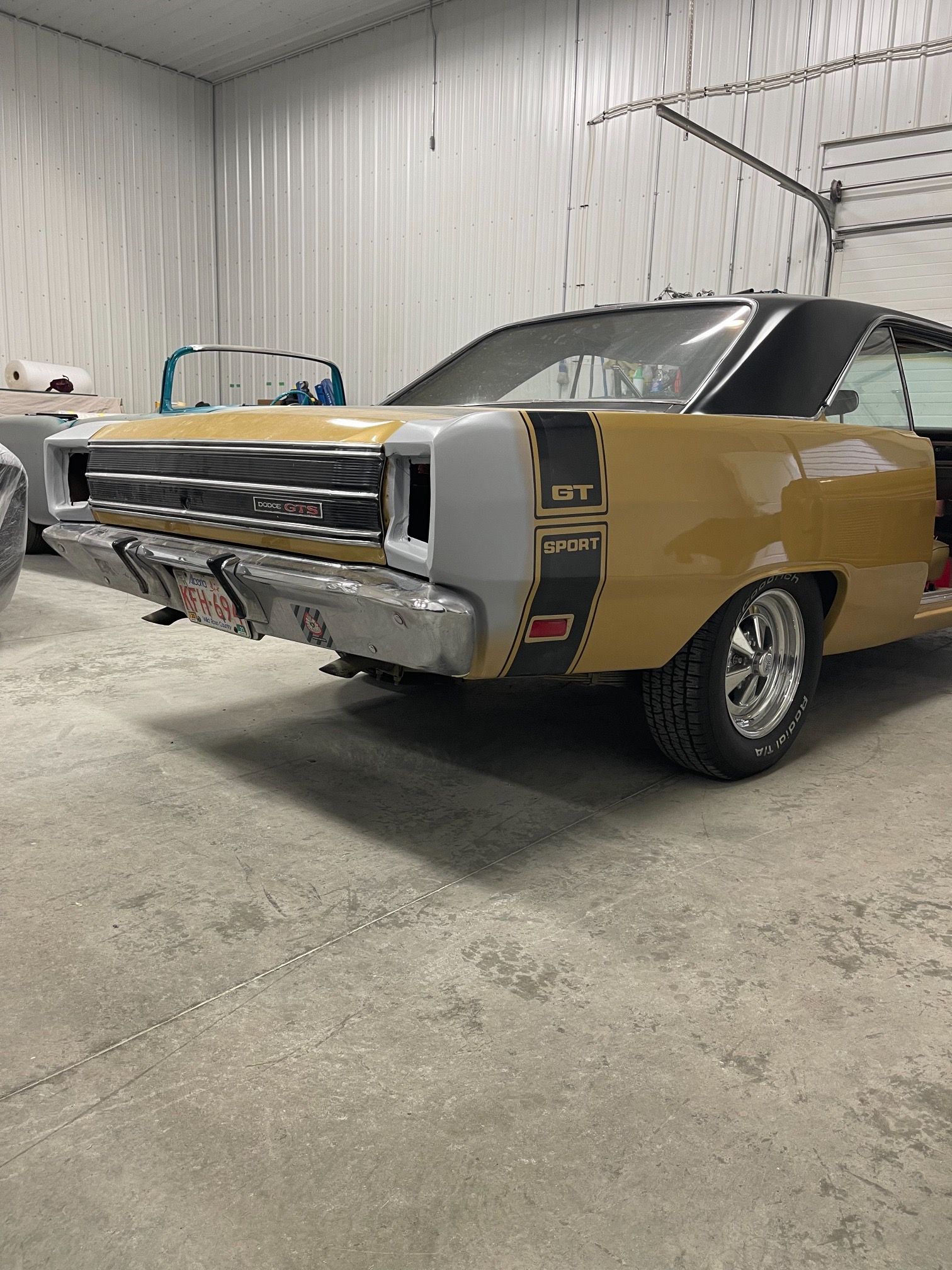 A yellow car is parked in a garage next to a white car.