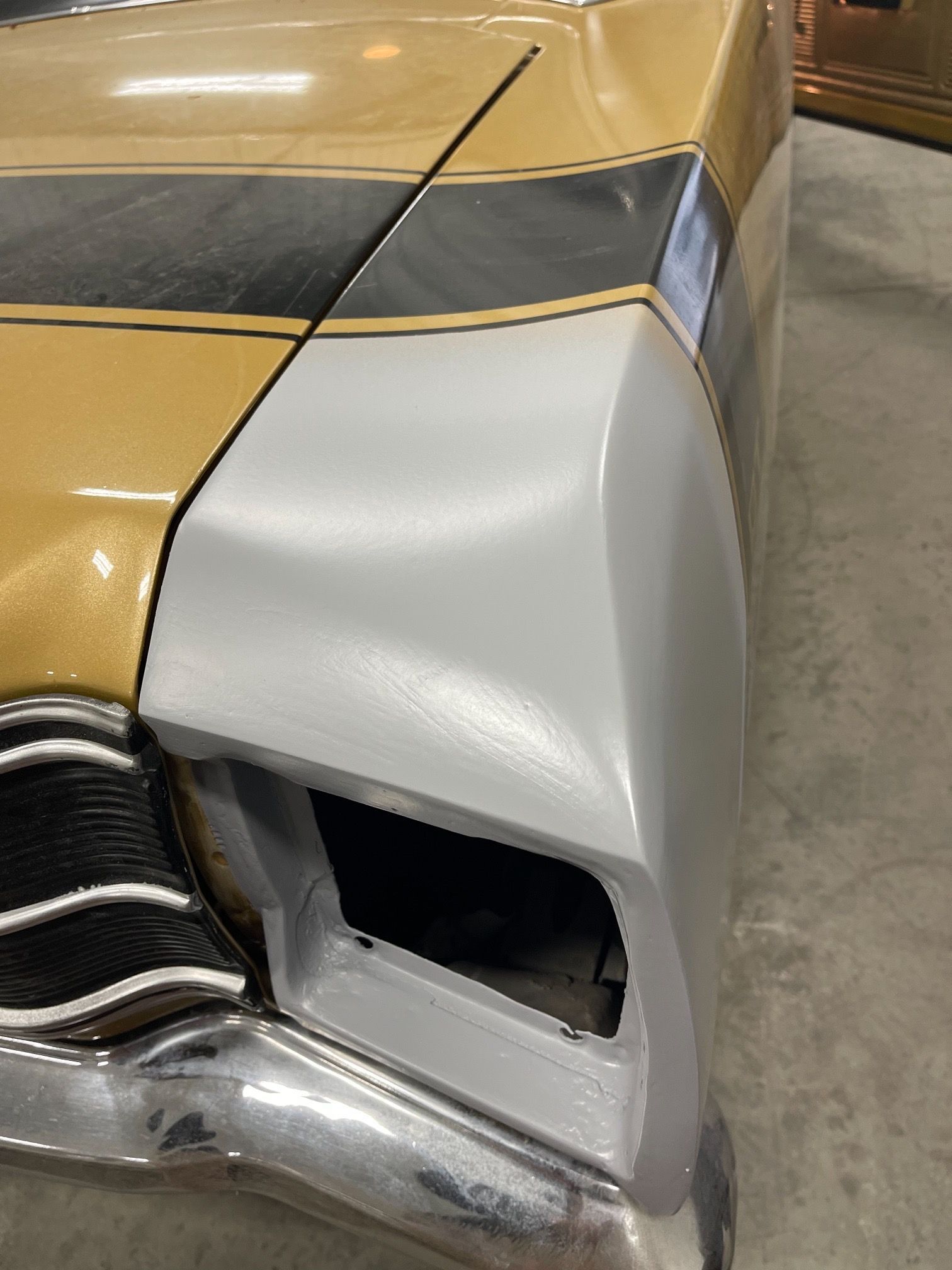 A close up of a car 's front bumper in a garage.