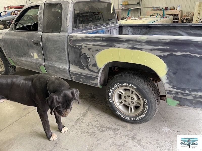 A dog is standing next to a truck that is being painted.