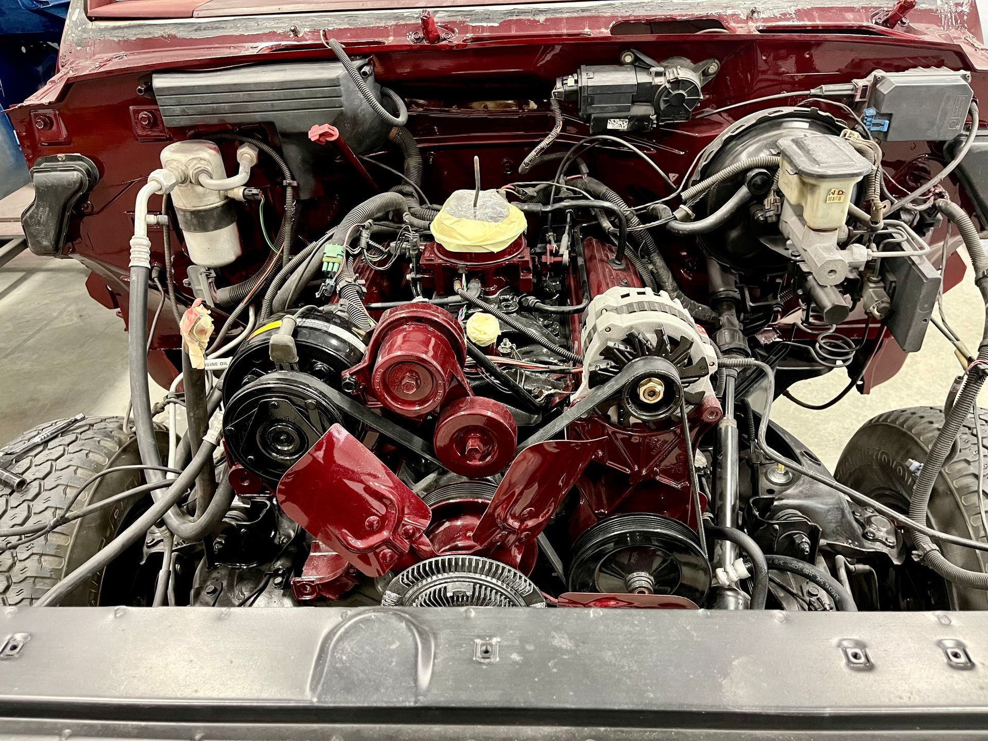 A close up of a red car engine with the hood open.
