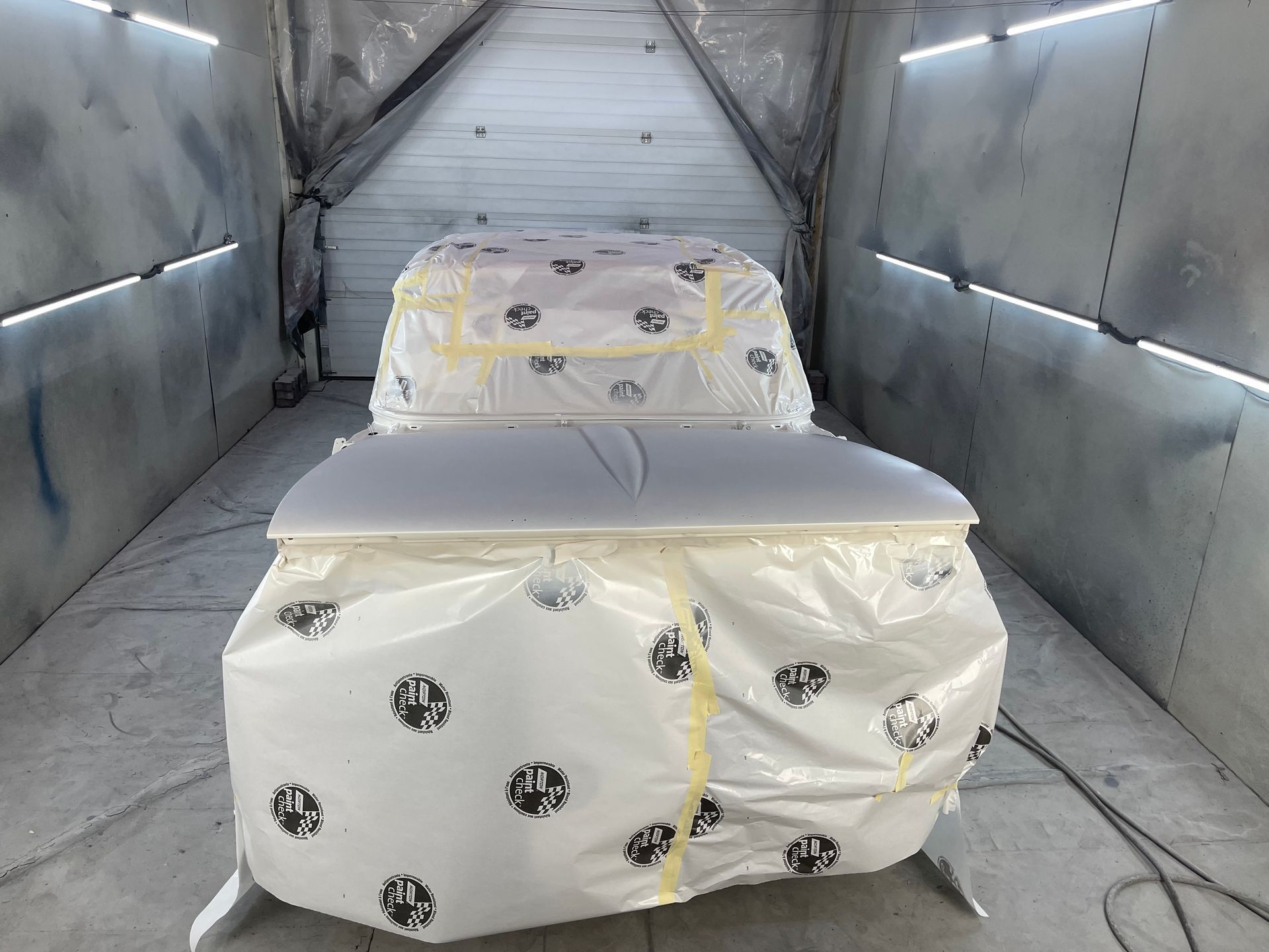 A car is wrapped in plastic in a paint booth.