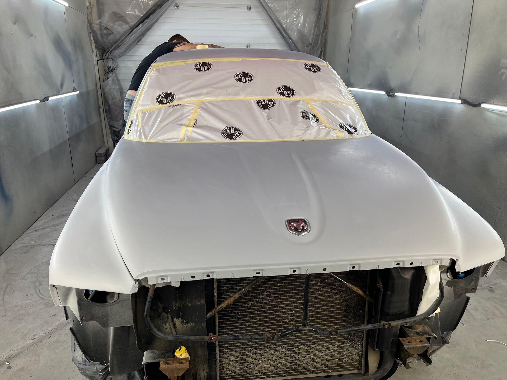 A white car is being painted in a paint booth