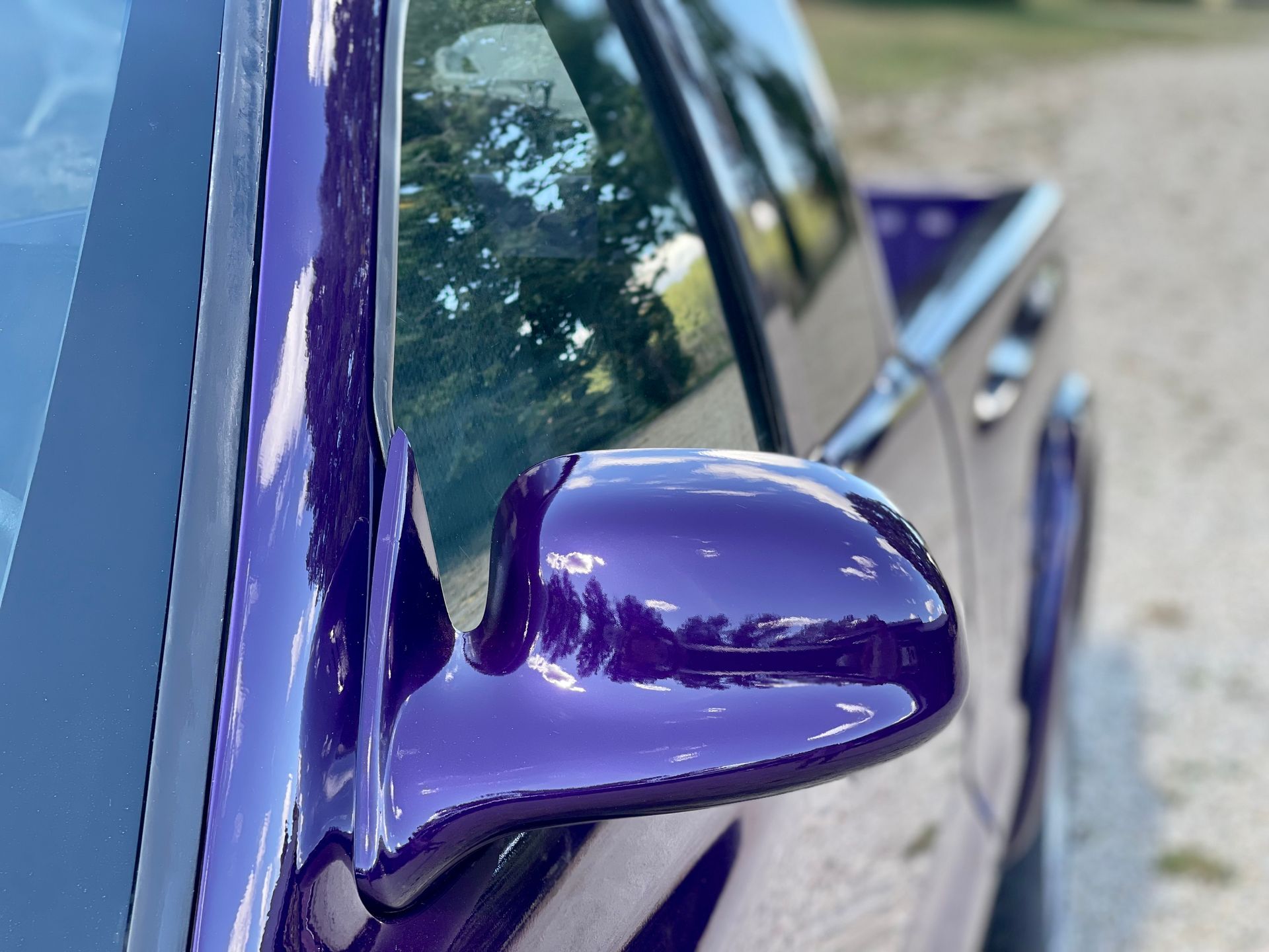 A close up of a purple car 's side mirror