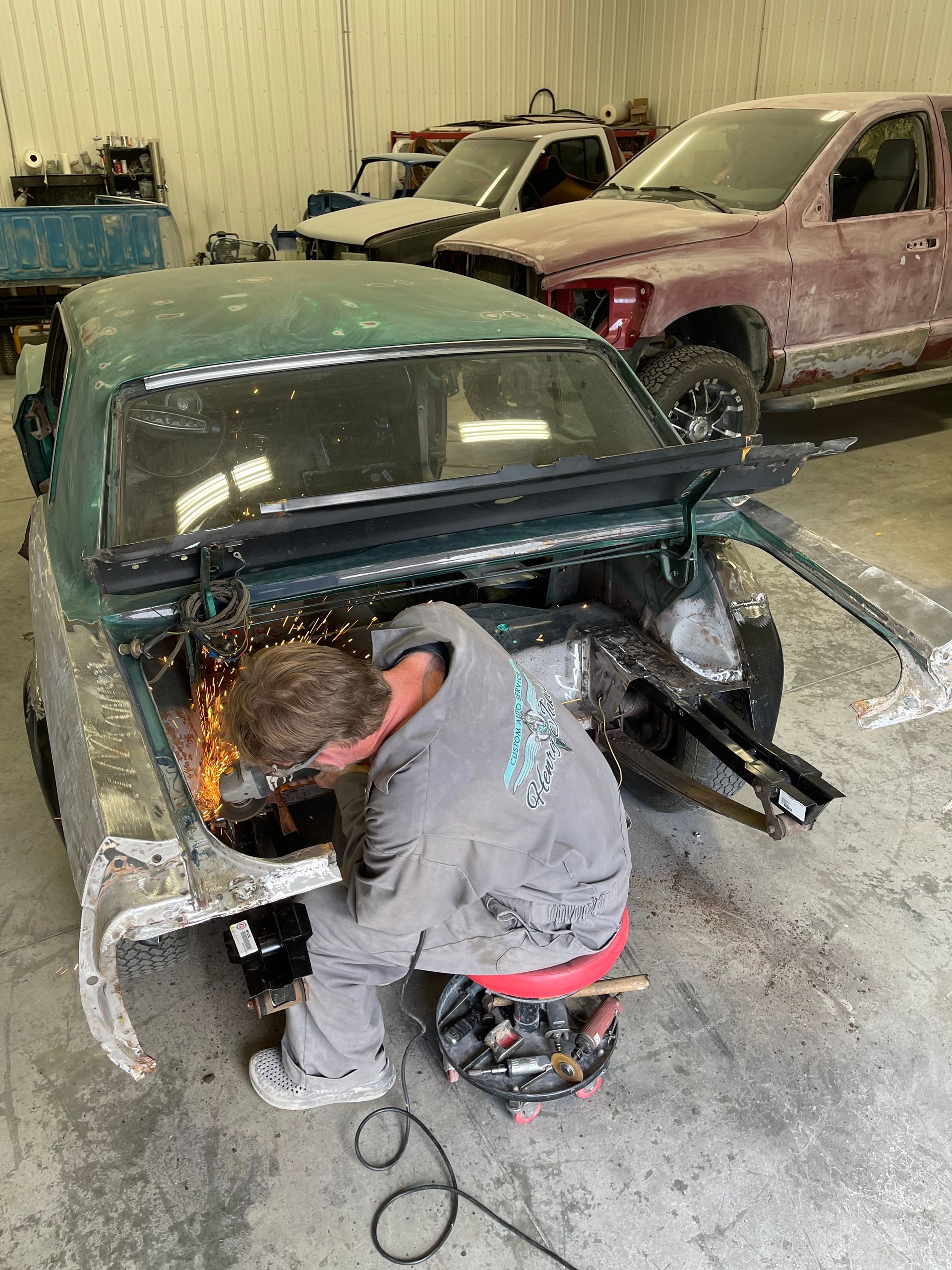 A man is welding a car in a garage.