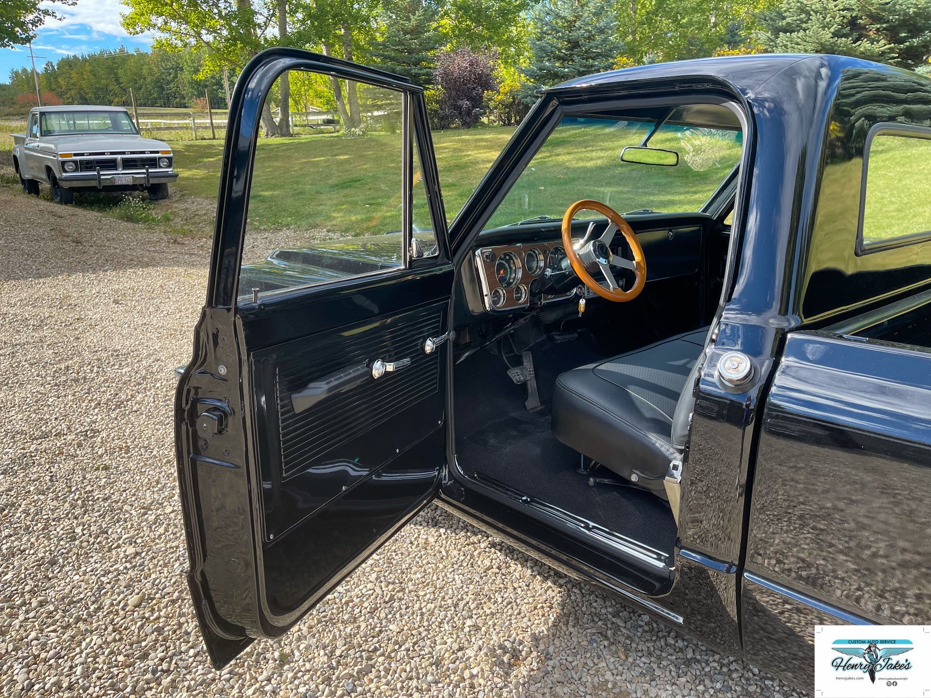 A black truck with its doors open and a white car parked behind it.