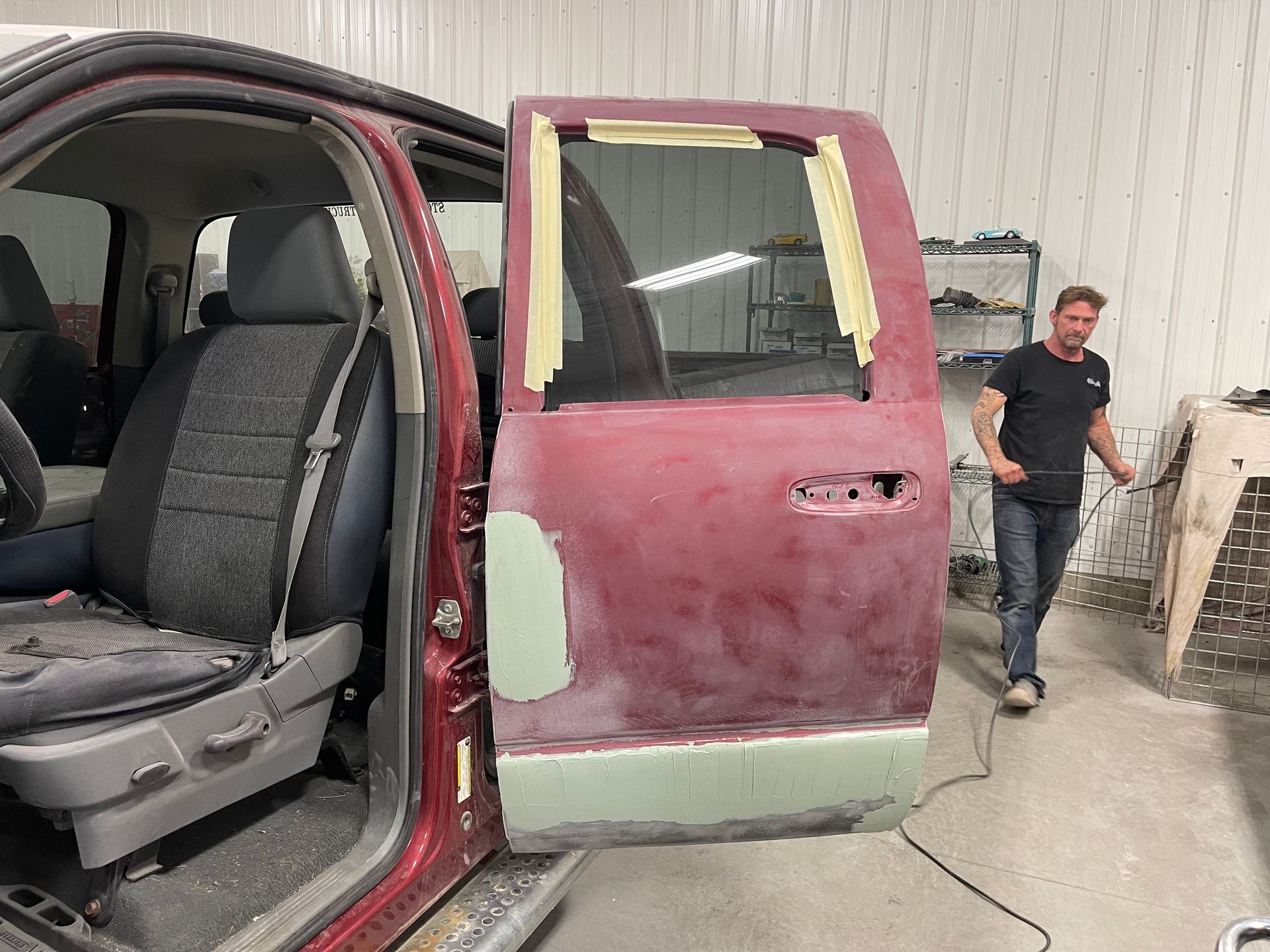 A man is working on a red truck in a garage.