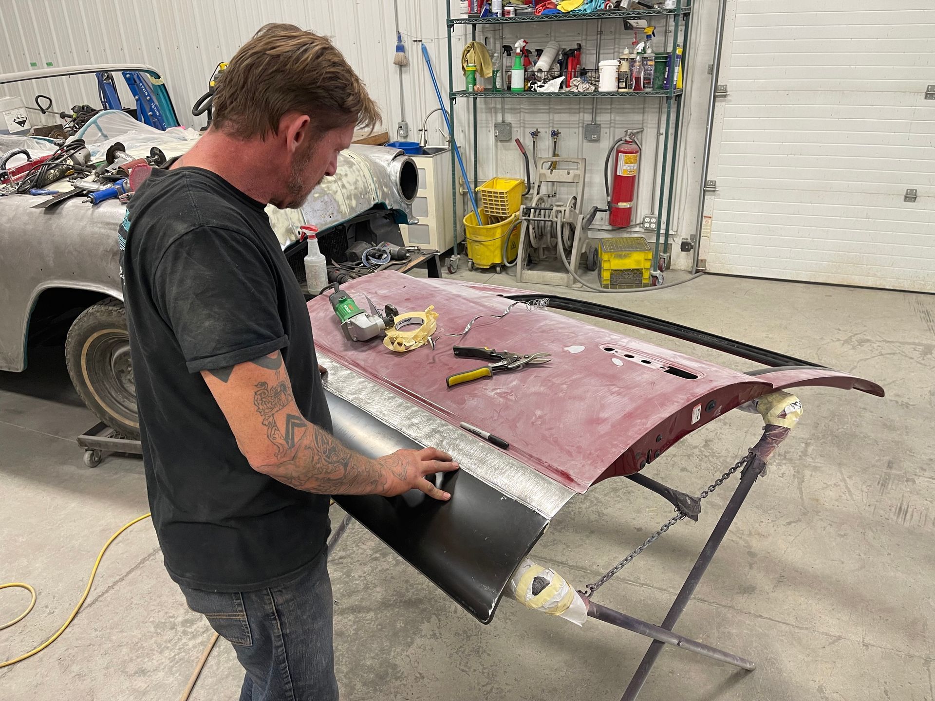 A man is working on a car door in a garage.
