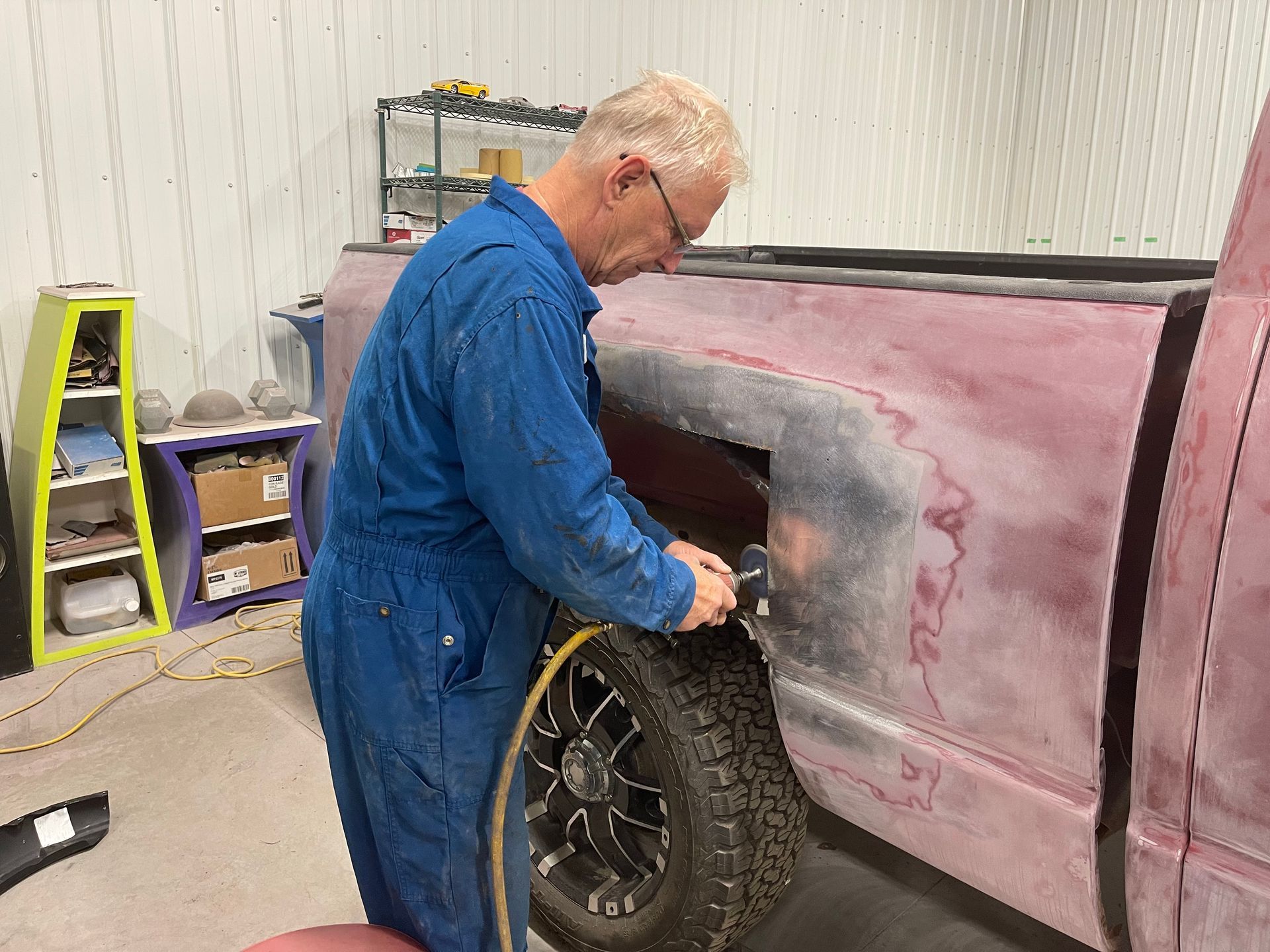 A man in a blue jumpsuit is working on a truck in a garage.