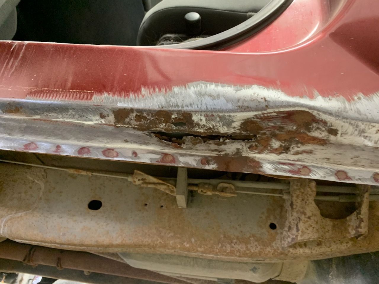 A close up of a red car with rust on it