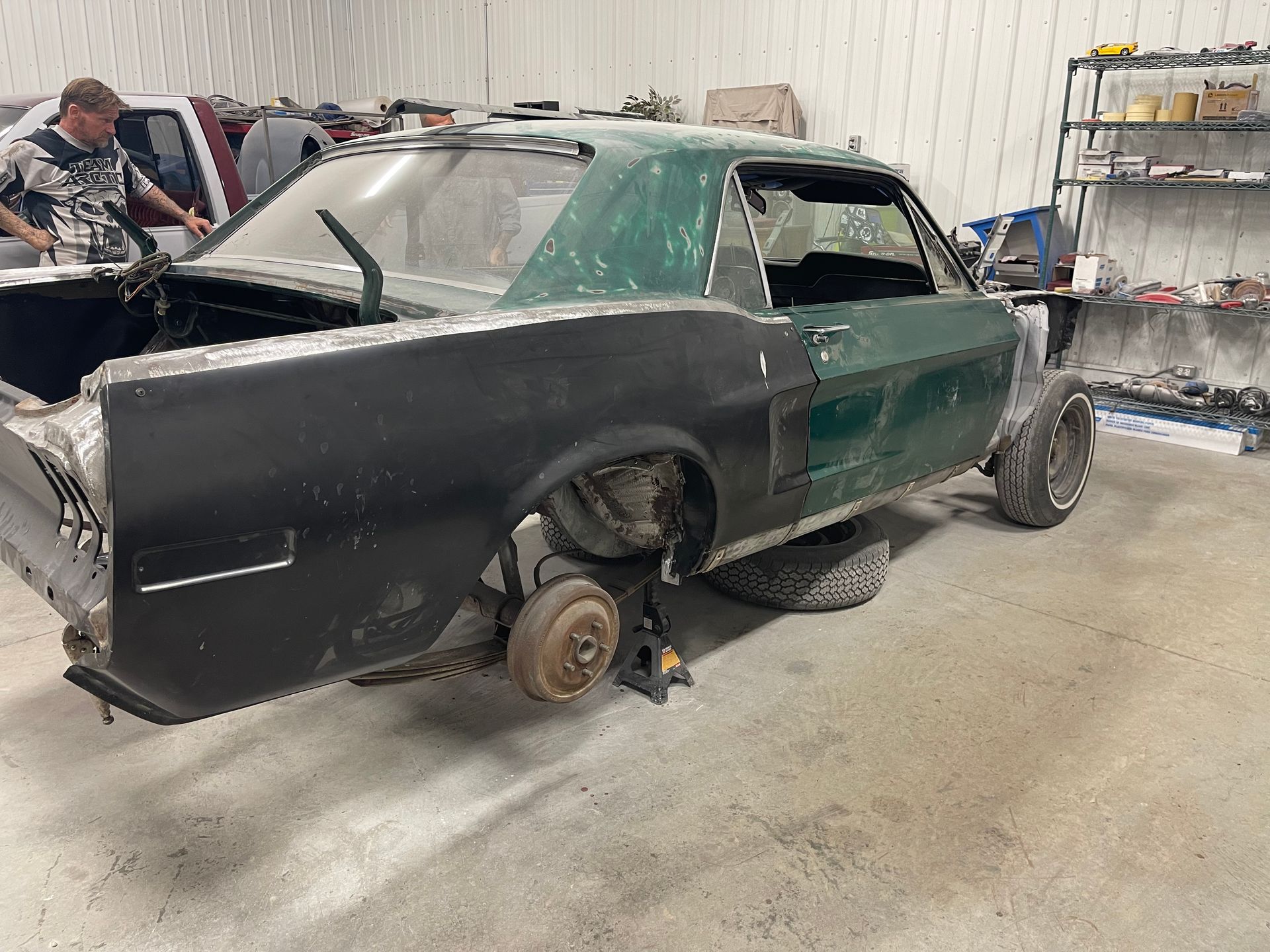 A man is working on a green mustang in a garage.