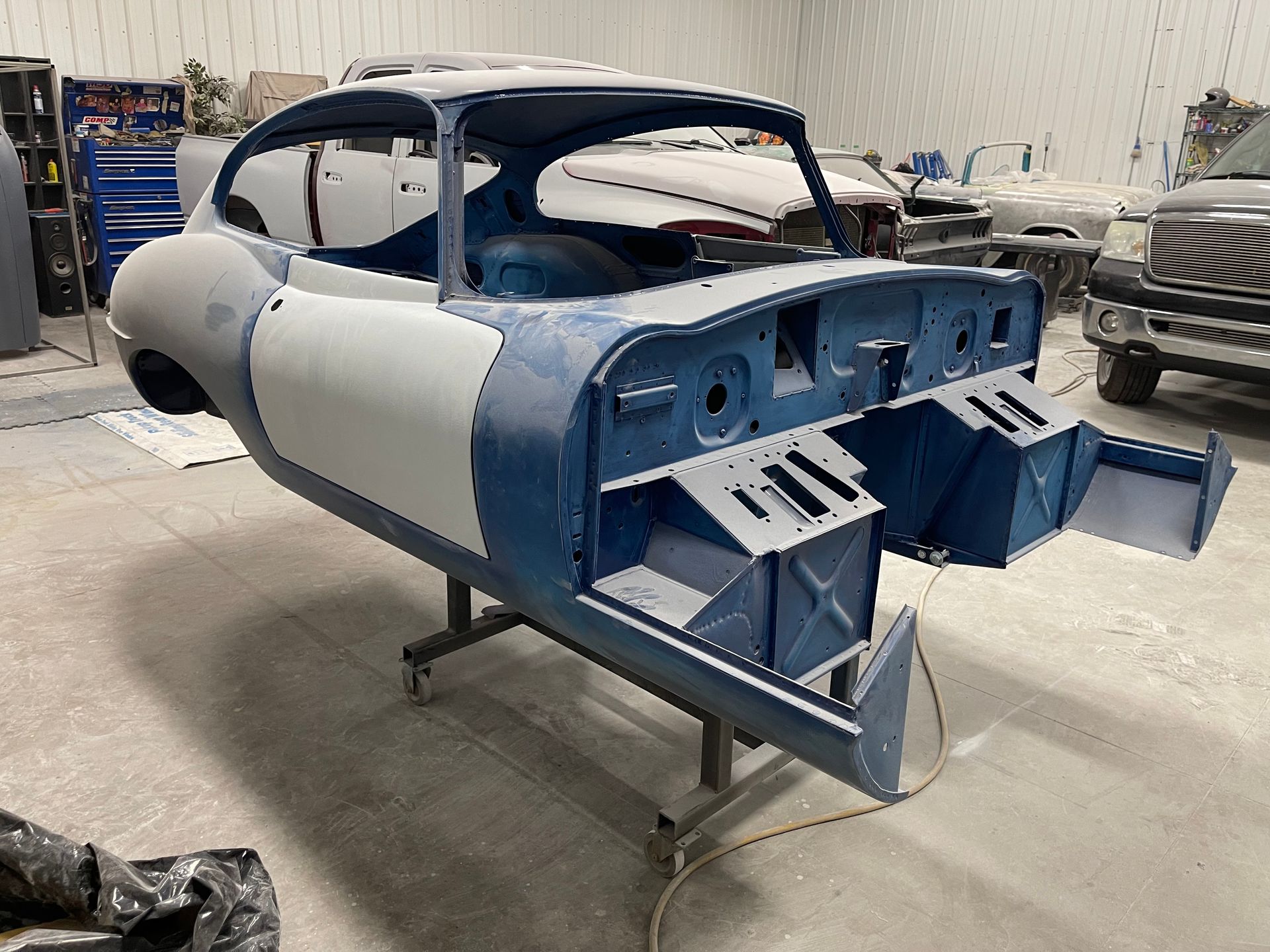 A blue and white car is sitting on a stand in a garage.