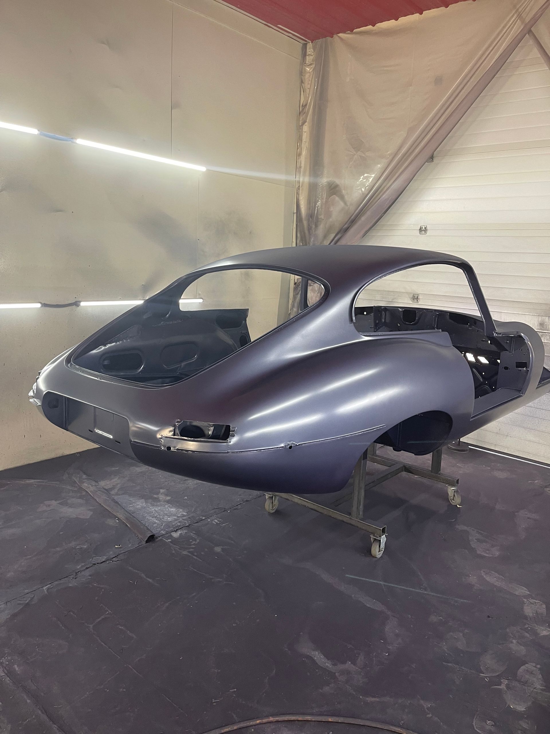 A gray car is sitting on a cart in a garage.