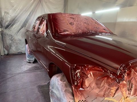 A red car is being painted in a garage.