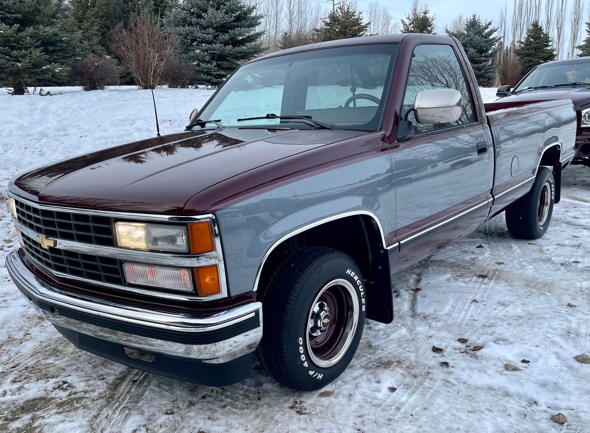 A red and gray truck is parked in the snow