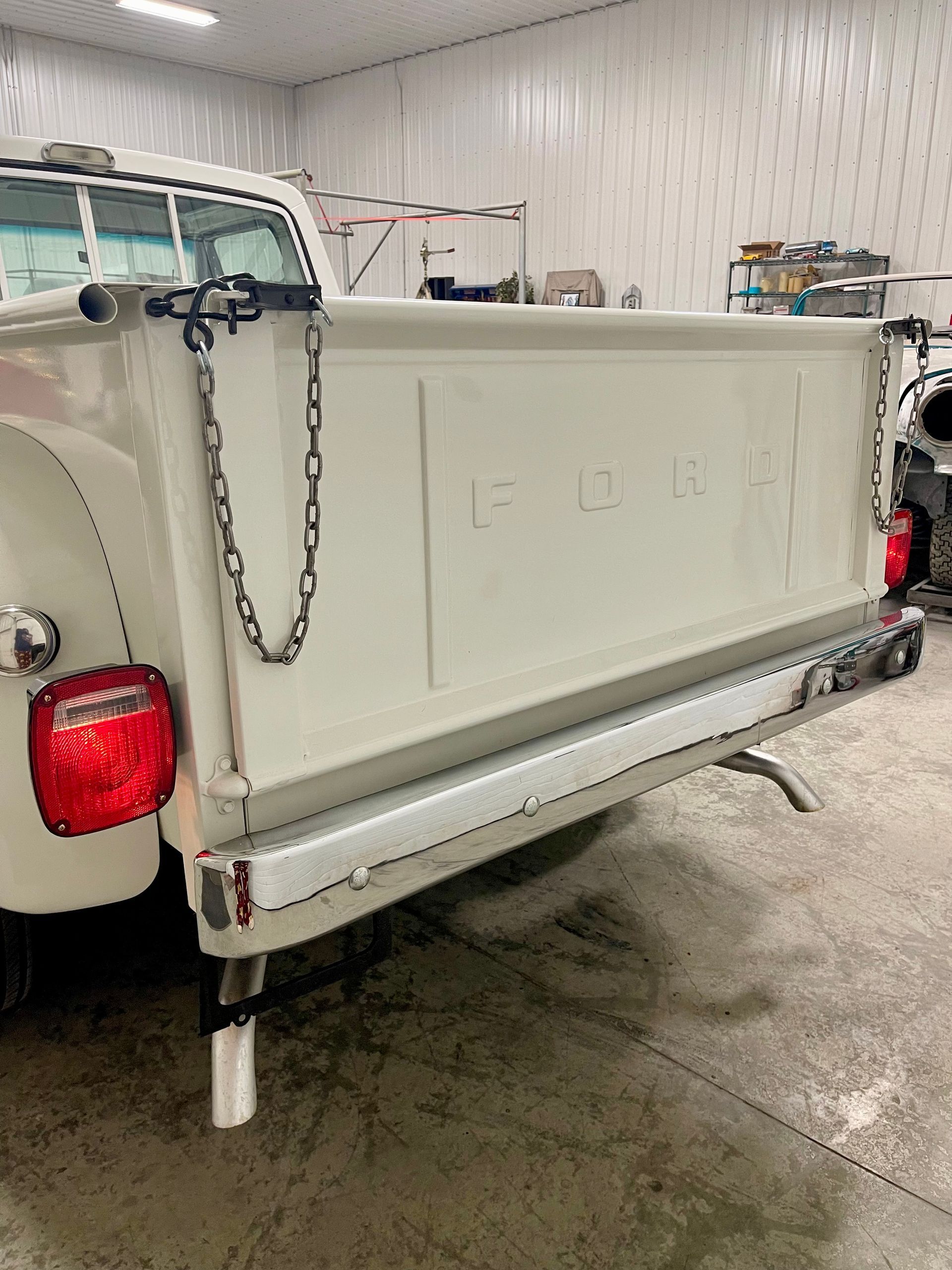 A white truck with a chain attached to the back of it is parked in a garage.
