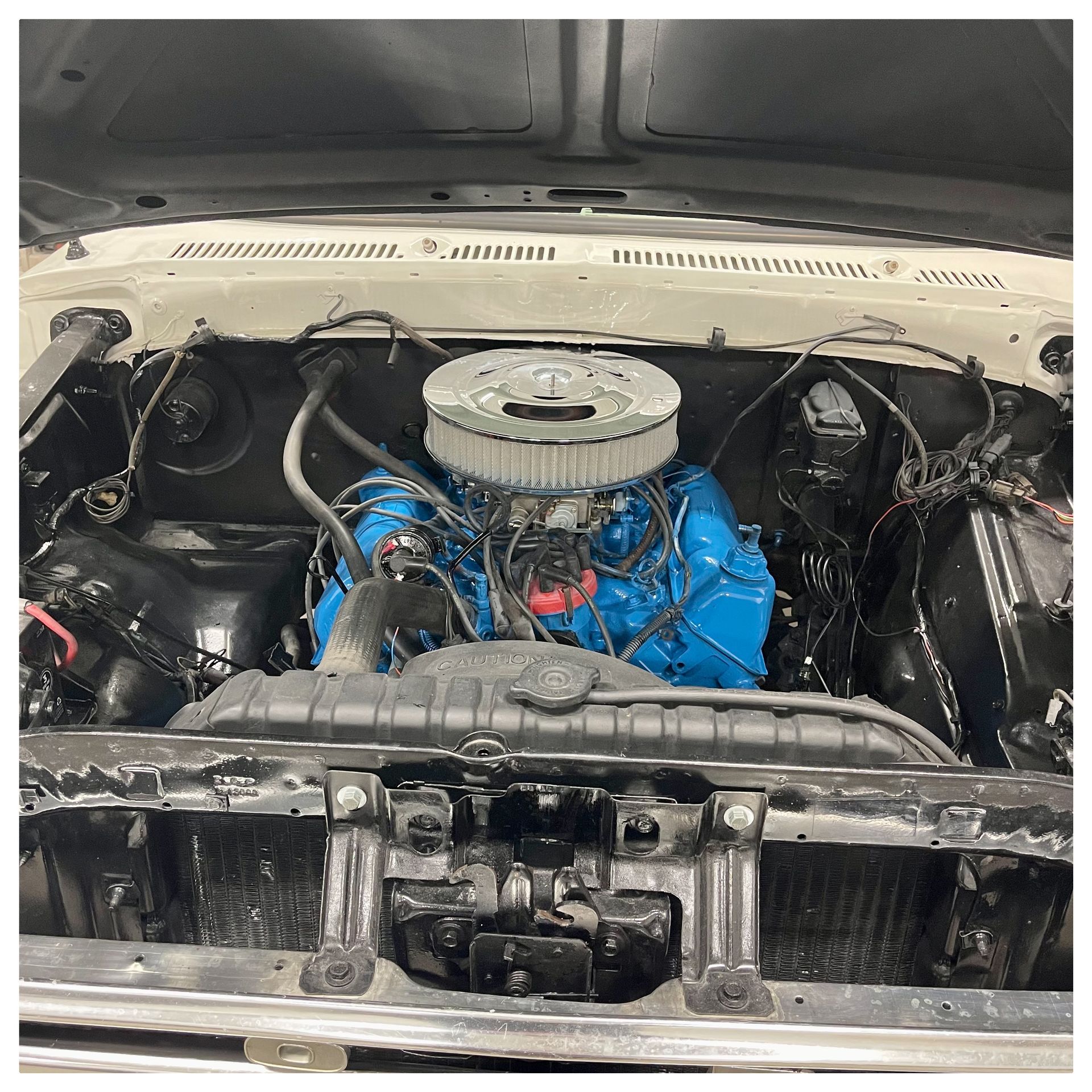 A close up of the engine of a car with the hood open.