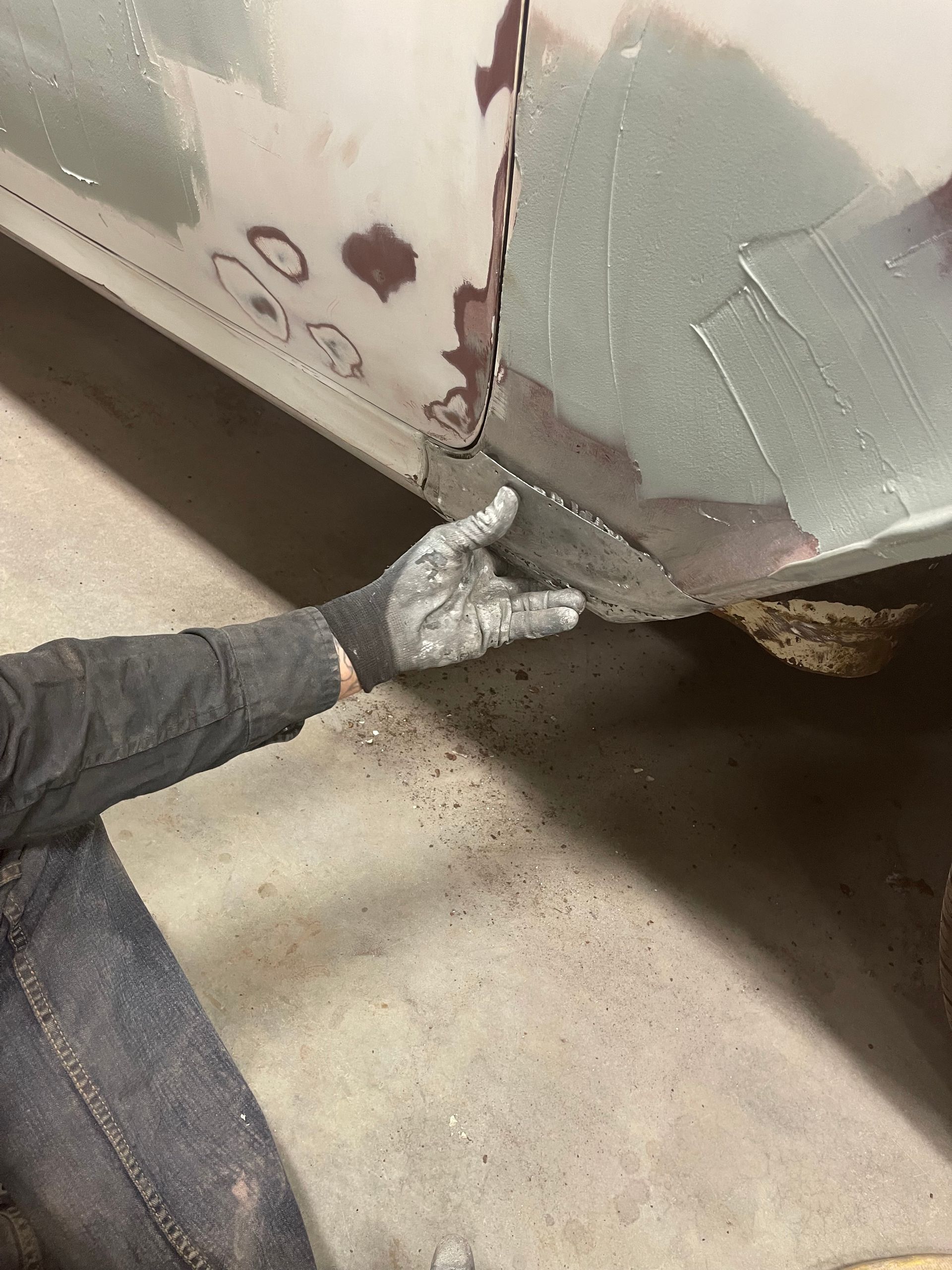 A person wearing gloves is working on a car in a garage.