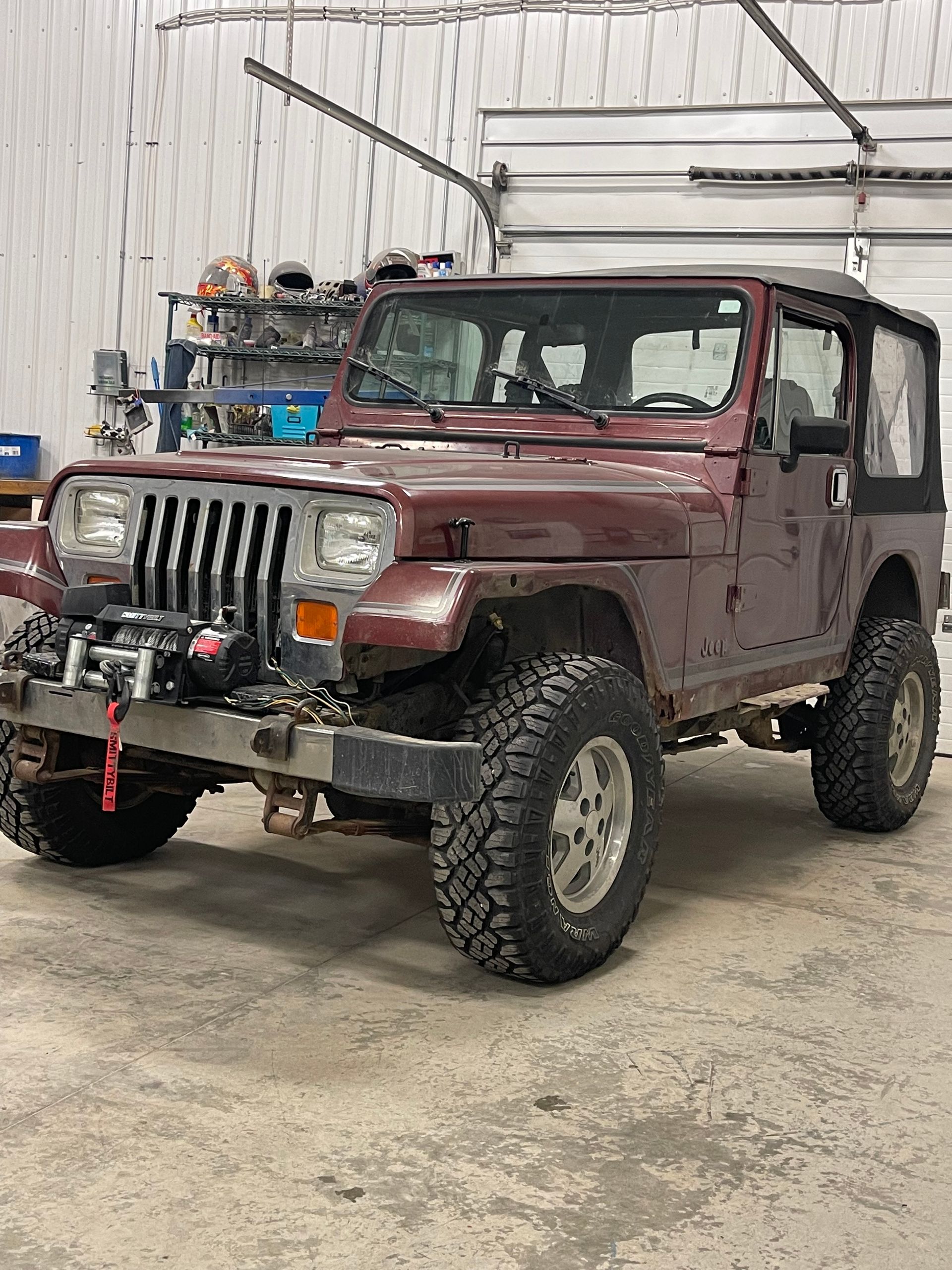 A red jeep is parked in a garage.