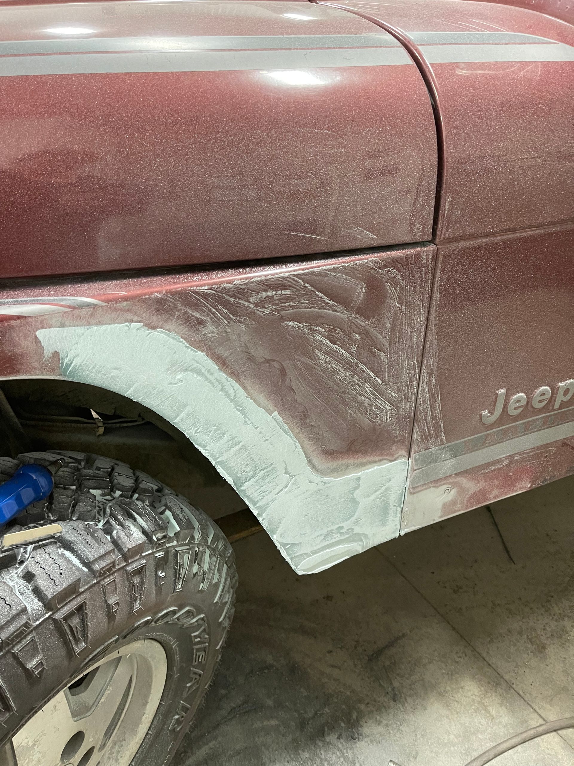 A dirty jeep is sitting in a garage.