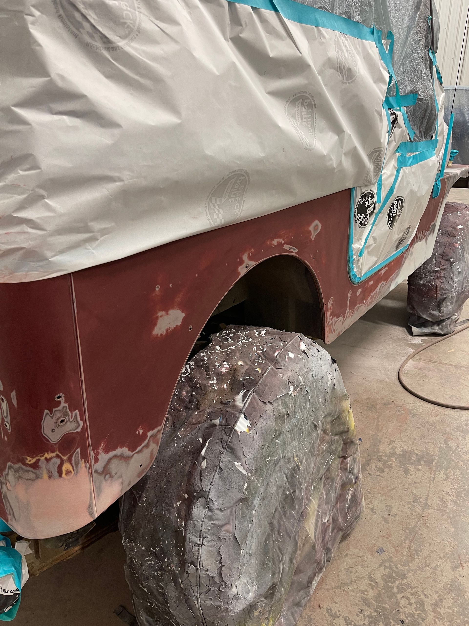 A jeep is being painted in a garage.