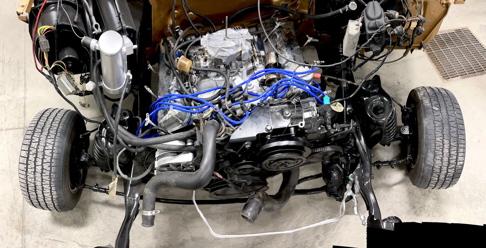 A close up of a car engine with a lot of wires coming out of it.